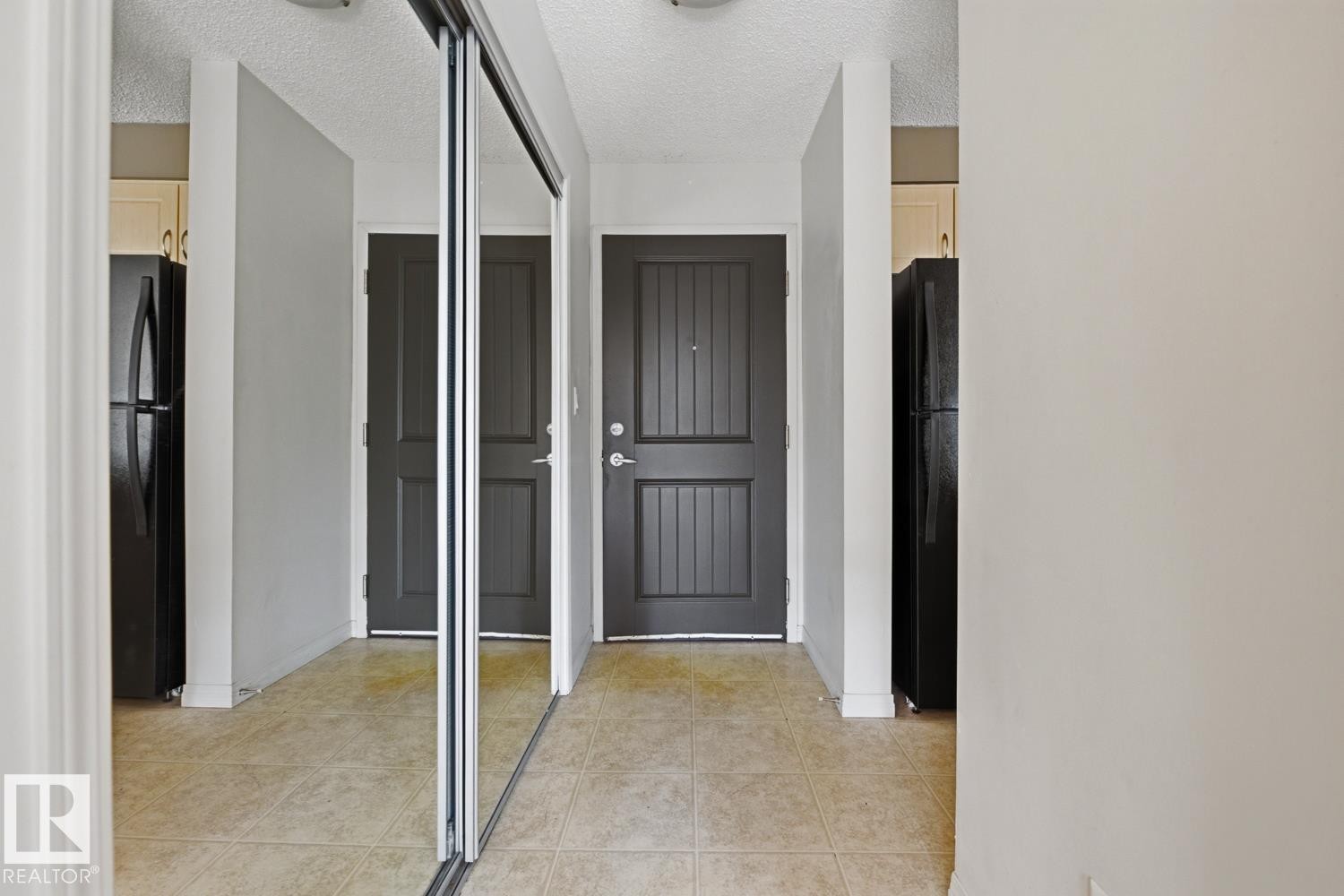 Entryway featuring ceramic tile flooring, a mirrored closet, and two panel doors - #312 13908 136 St Nw, Edmonton, AB - Indoor Photo Showing Other Room