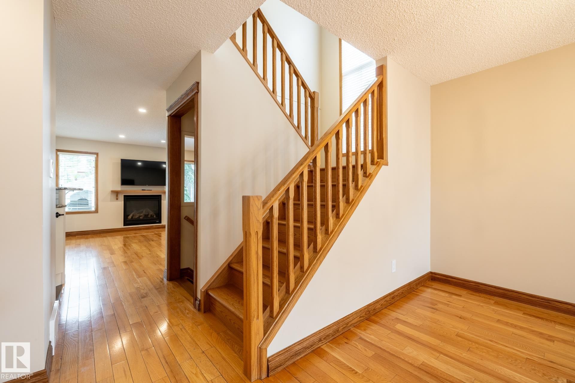 Hardwood flooring throughout the main level and staircase - 4632 151 Street, Edmonton, AB - Indoor Photo Showing Other Room With Fireplace