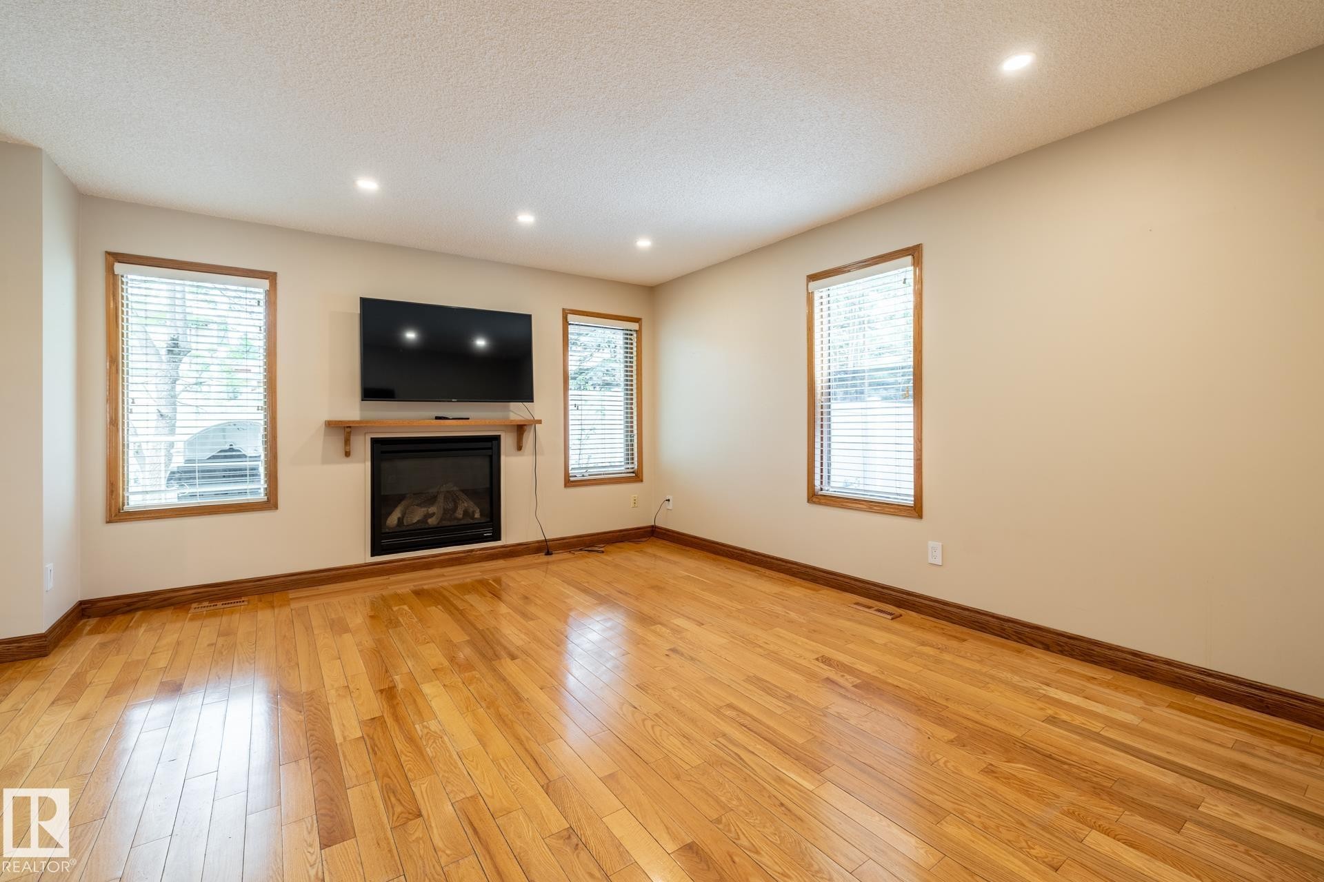 Living area featuring rich wood-finish flooring, an inset fireplace with a wood mantle, and recessed ceiling lighting - 4632 151 Street, Edmonton, AB - Indoor With Fireplace