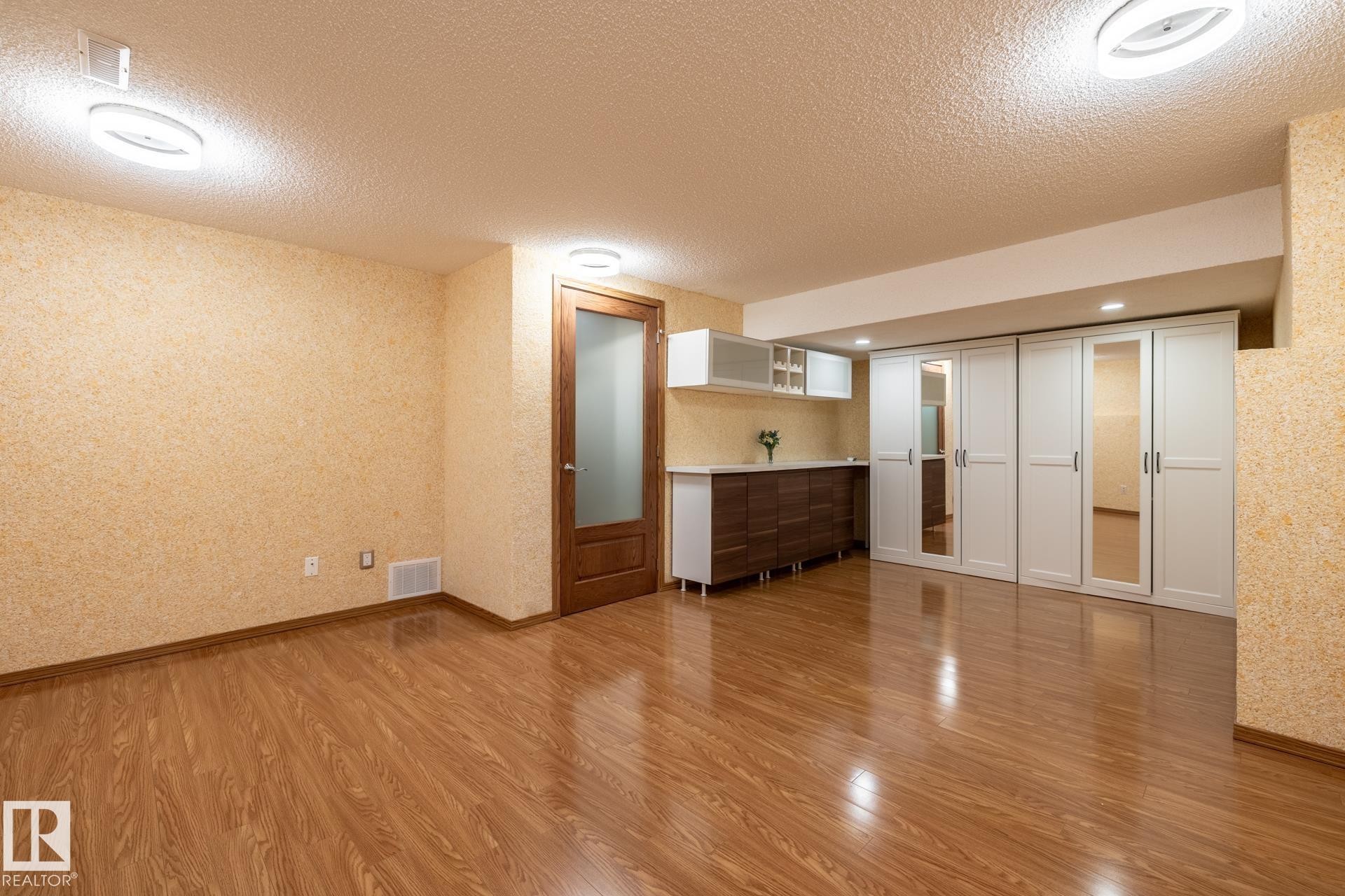 Spacious room featuring wood-finish flooring and textured wall finishes - 4632 151 Street, Edmonton, AB - Indoor