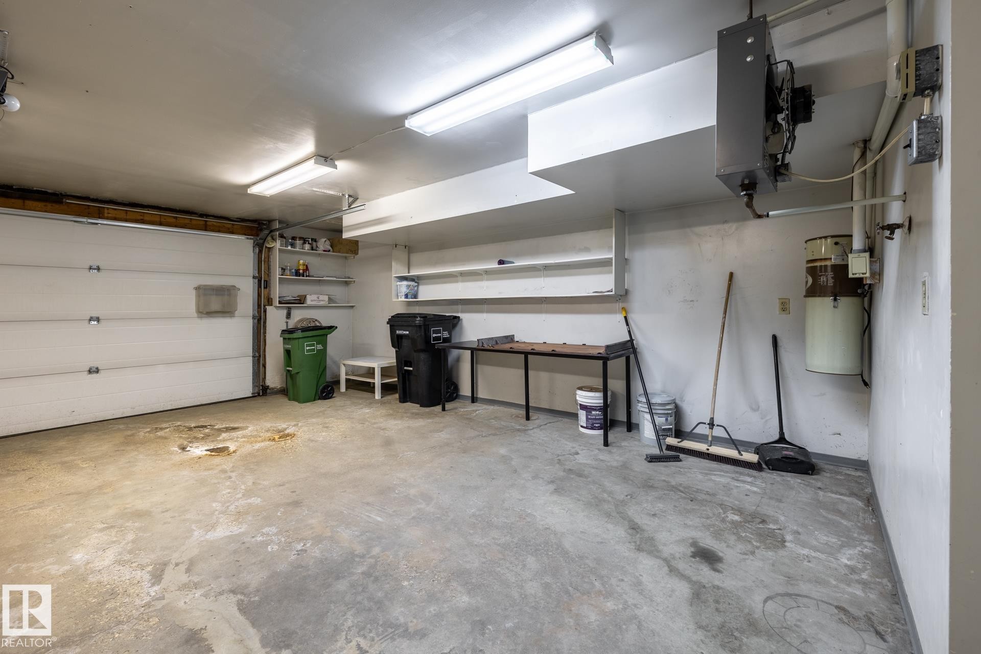 Garage with concrete flooring, fluorescent lighting, and a white overhead door - 4632 151 Street, Edmonton, AB - Indoor Photo Showing Garage