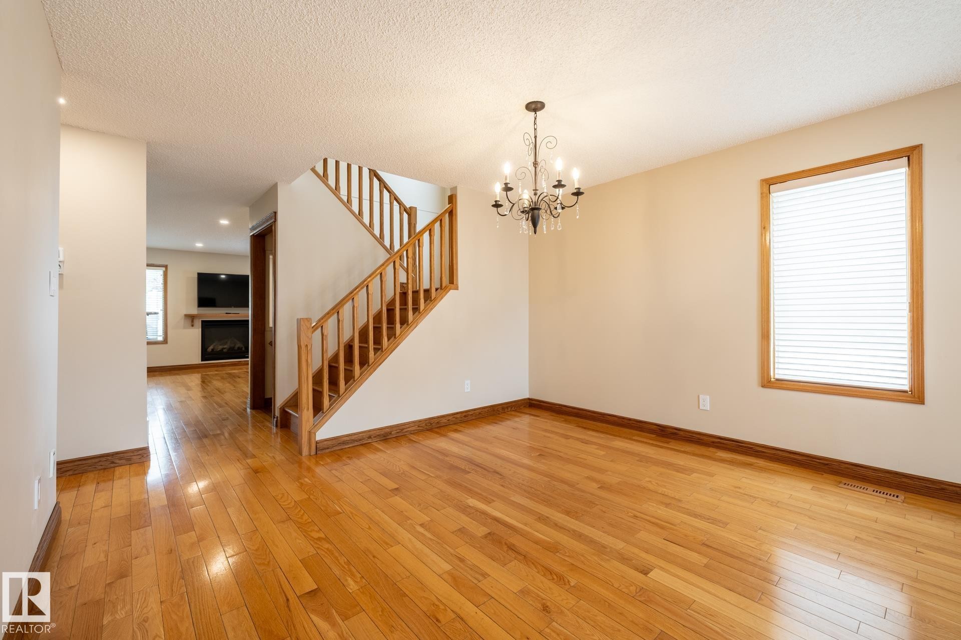 Hardwood flooring throughout, featuring a natural wood staircase with matching railing, baseboards, and window trim - 4632 151 Street, Edmonton, AB - Indoor Photo Showing Other Room