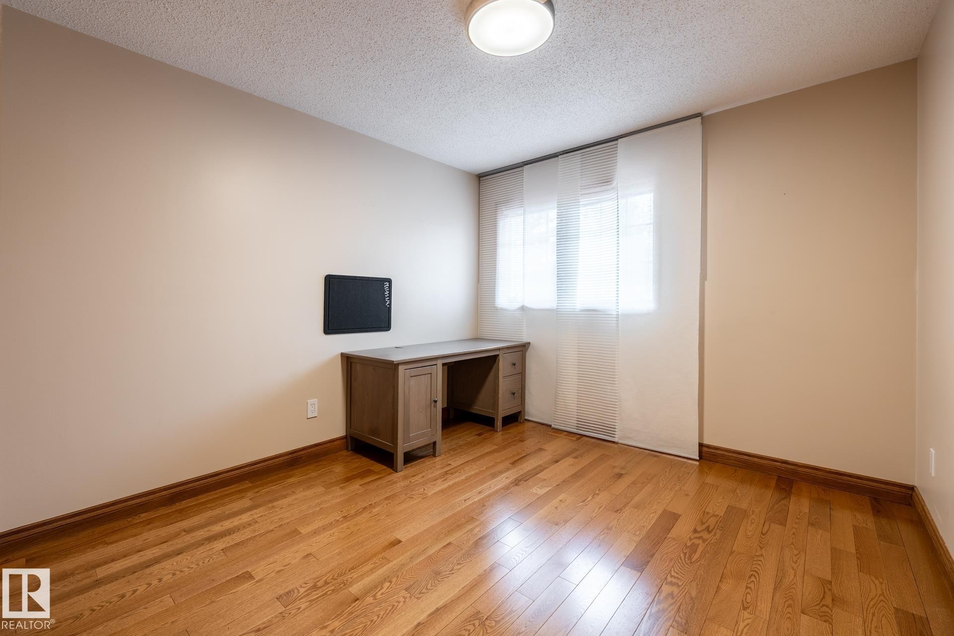 Room featuring wood-finish flooring, a window with panel blinds, and a flush mount ceiling light fixture - 4632 151 Street, Edmonton, AB - Indoor Photo Showing Other Room