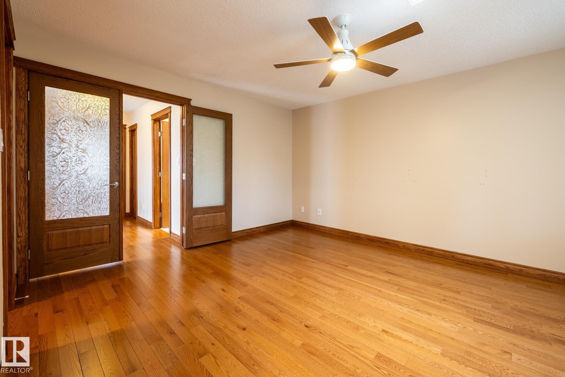 Hardwood flooring throughout, featuring wood-framed doors with decorative glass panels - 4632 151 Street, Edmonton, AB - Indoor Photo Showing Other Room