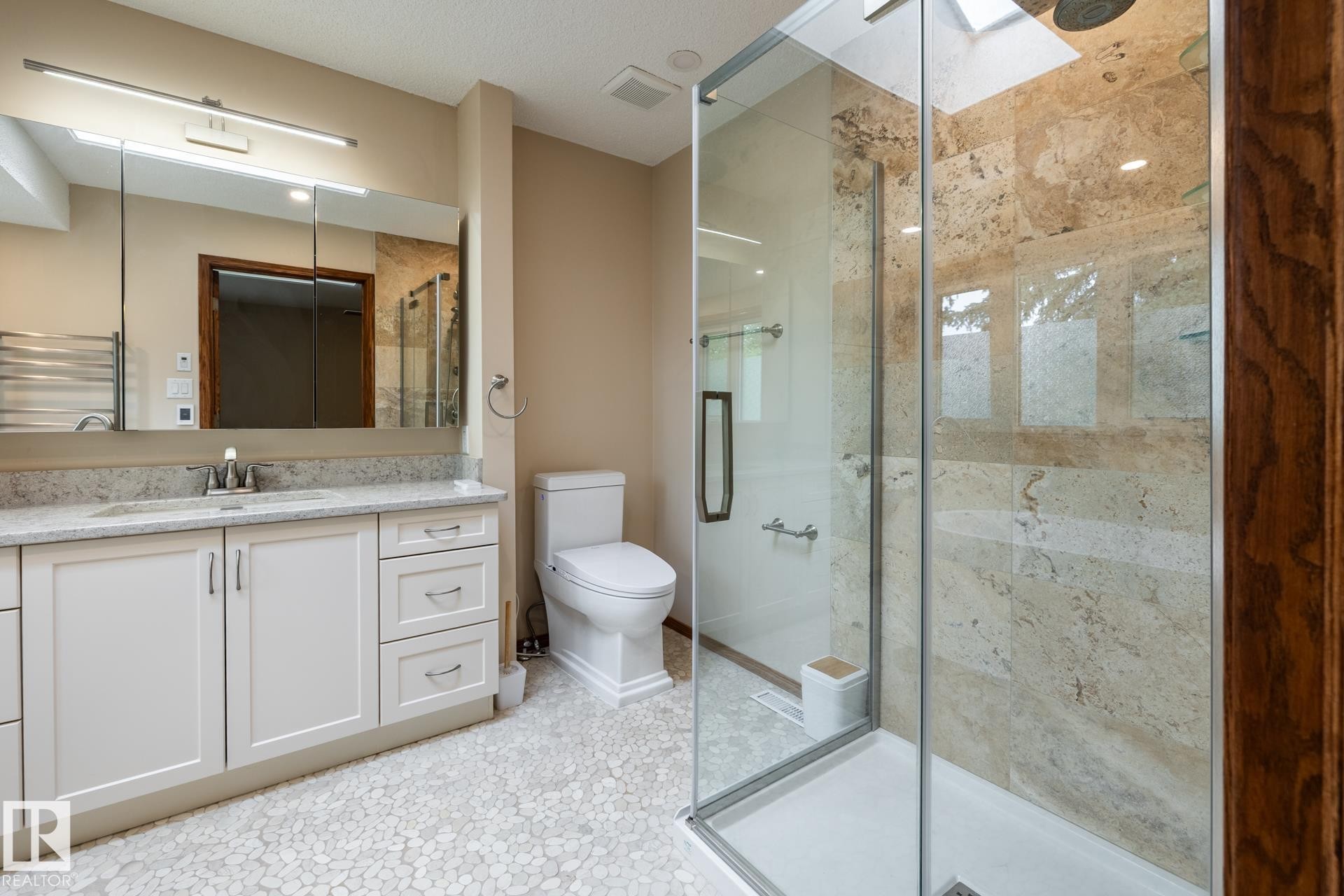 Bathroom featuring a frameless glass shower enclosure with stone-tiled walls and a skylight - 4632 151 Street, Edmonton, AB - Indoor Photo Showing Bathroom