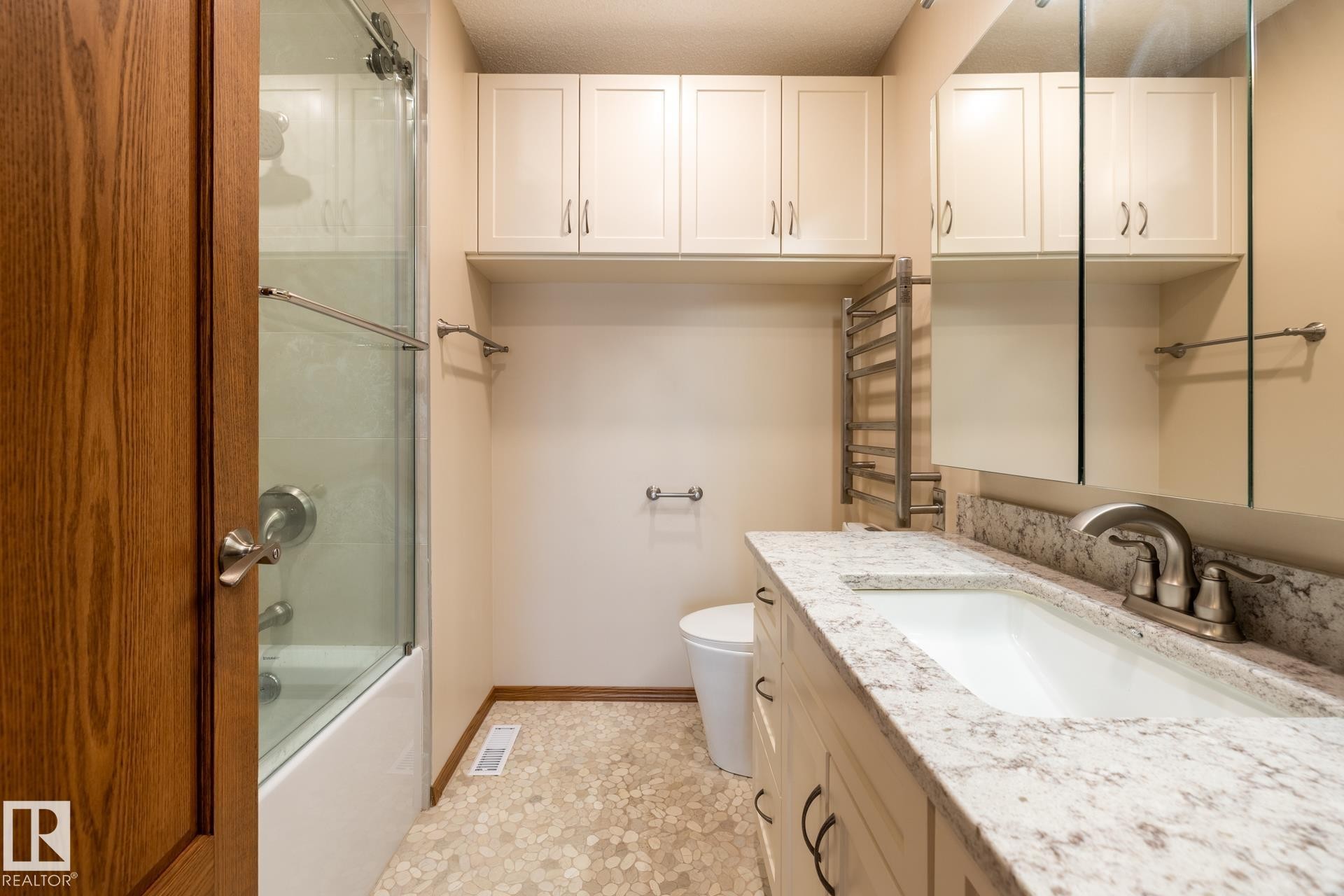 Bathroom featuring a vanity with an integrated sink, a speckled countertop, and brushed nickel fixtures - 4632 151 Street, Edmonton, AB - Indoor Photo Showing Bathroom