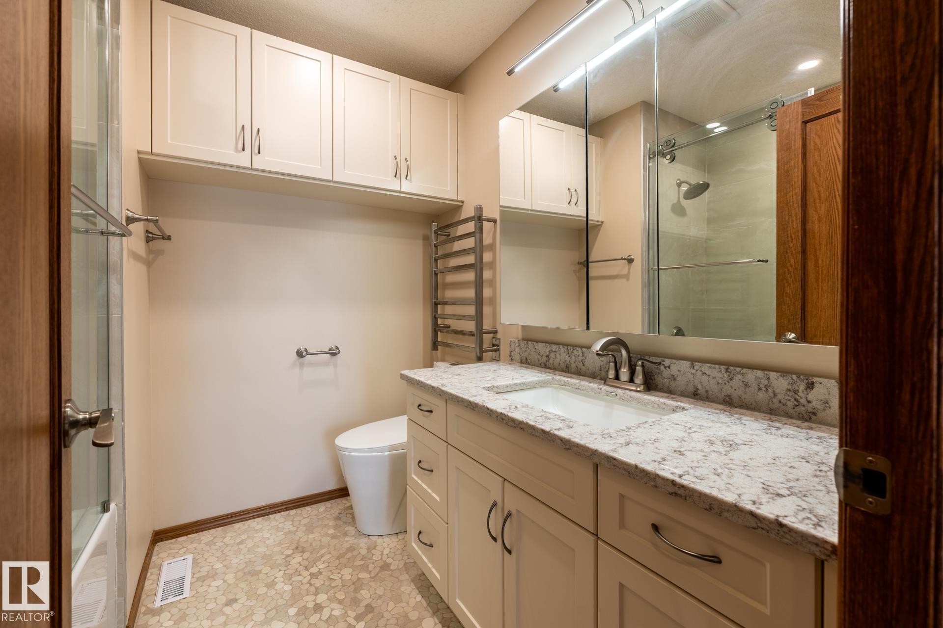 Bathroom featuring a white vanity with a light-colored countertop, an integrated sink, and an expansive mirror - 4632 151 Street, Edmonton, AB - Indoor Photo Showing Bathroom