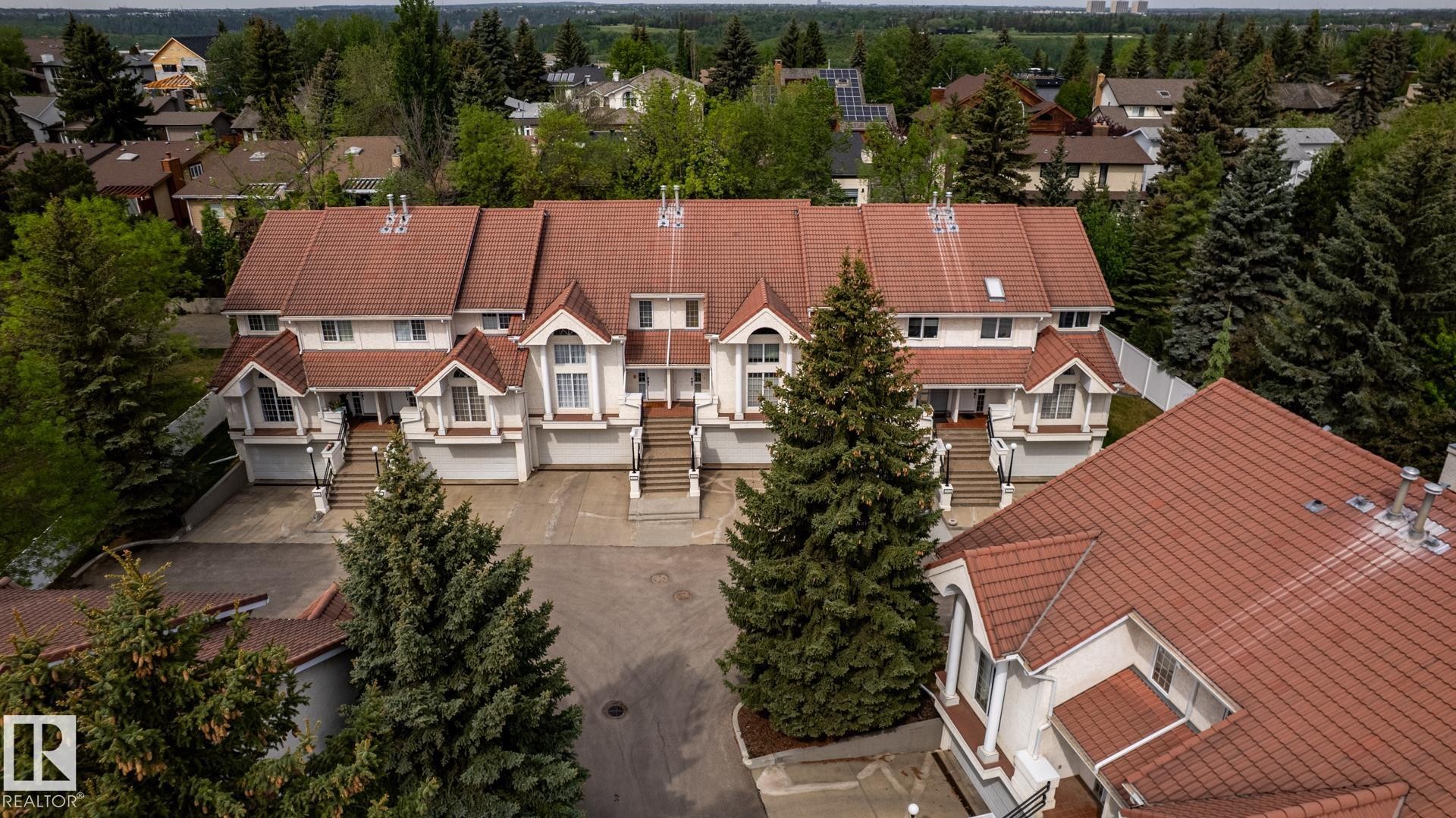 Townhome complex featuring white facades, red tile roofing, and multiple gables - 4632 151 Street, Edmonton, AB - Outdoor With Facade