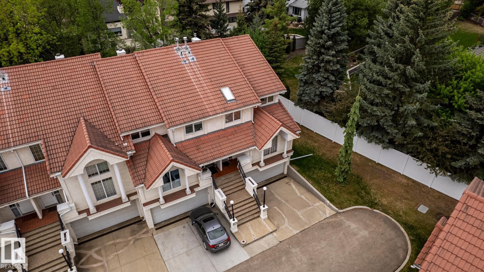 Multi-level townhome exterior featuring an orange tile roof, white facade, and integrated garage - 4632 151 Street, Edmonton, AB - Outdoor With Deck Patio Veranda