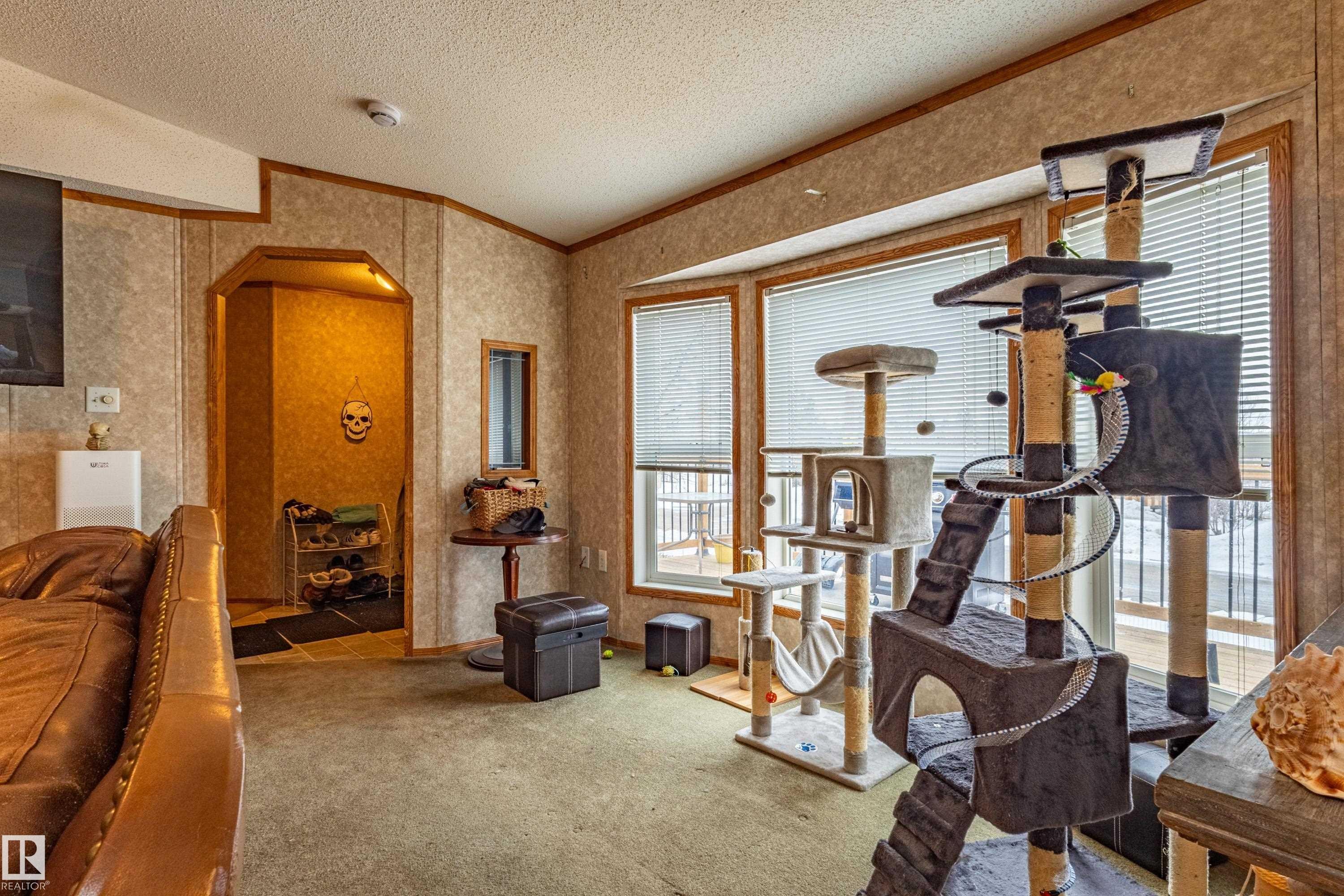 Living area featuring a bay window with horizontal blinds, textured wall panels with wood trim, and a recessed entryway - 1529 Range Road 272 Rural Parkland County, Alberta, Rural Parkland County, AB - Indoor Photo Showing Gym Room