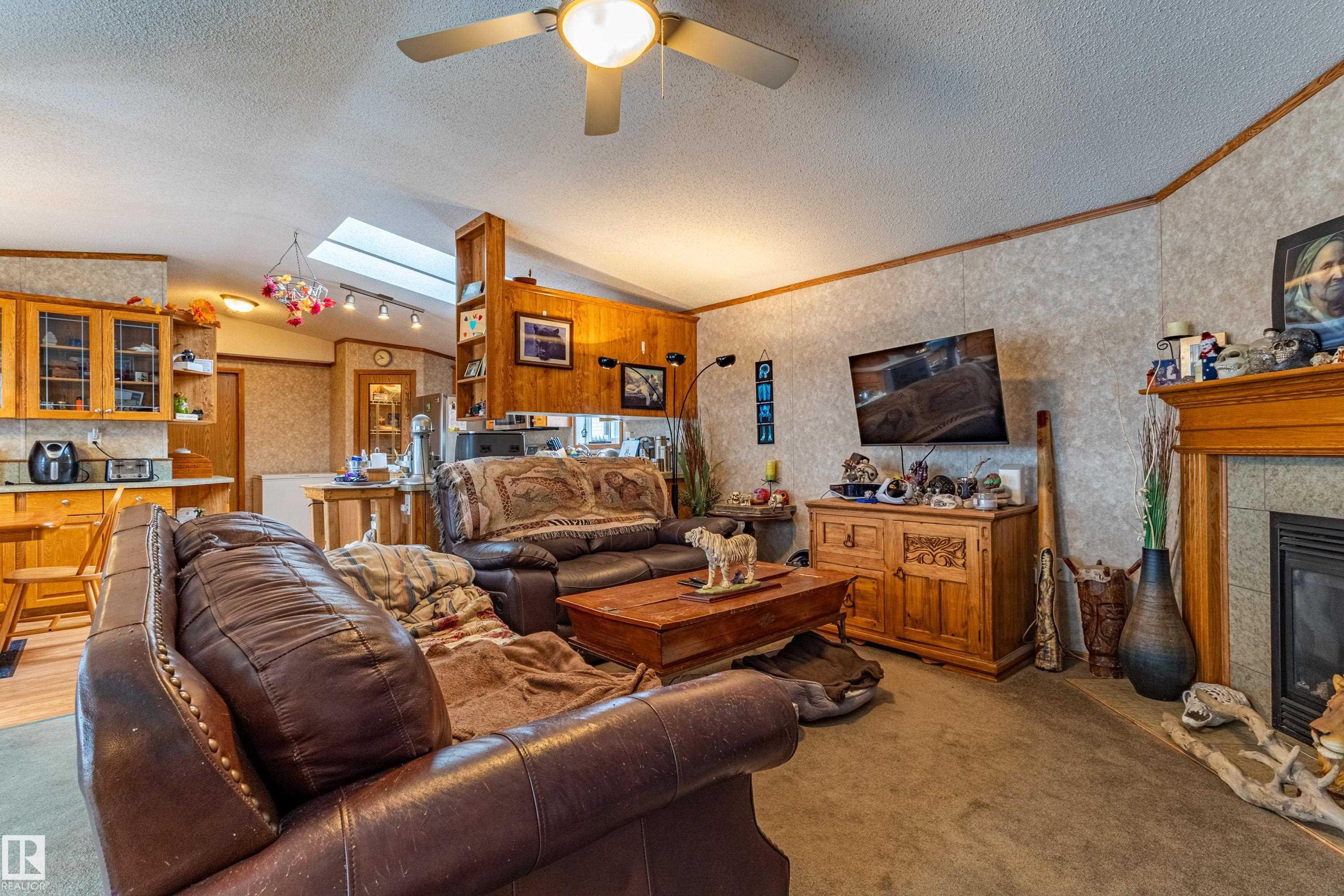 Living area featuring a ceiling fan, a prominent fireplace with a wood mantel, and built-in shelving - 1529 Range Road 272 Rural Parkland County, Alberta, Rural Parkland County, AB - Indoor Photo Showing Living Room With Fireplace