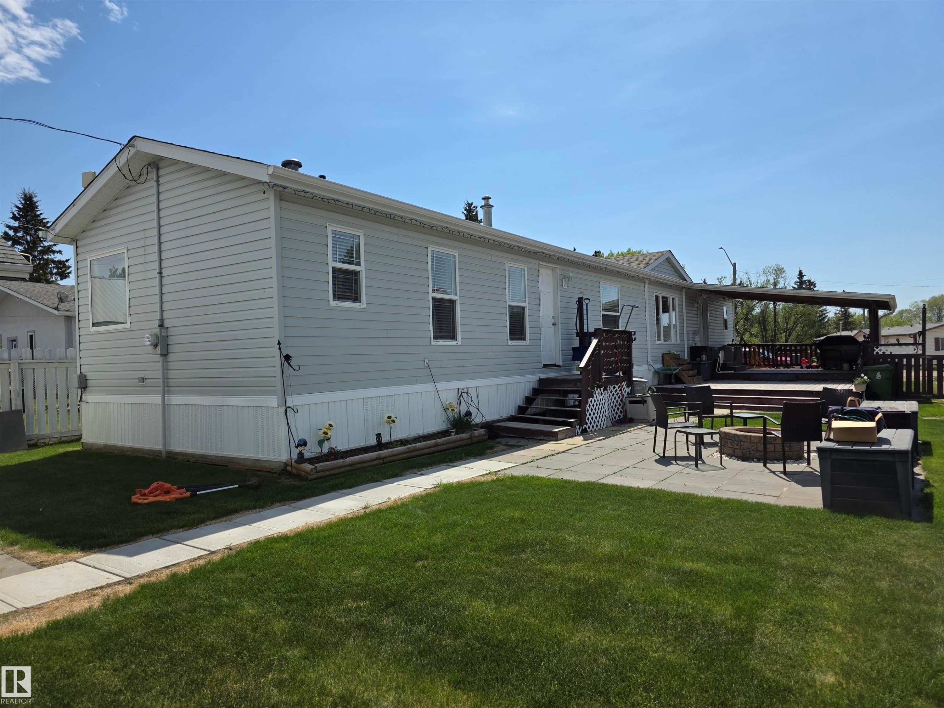 Exterior featuring light gray siding, white trim, and a covered deck - 5012 53 Ave, Breton, AB