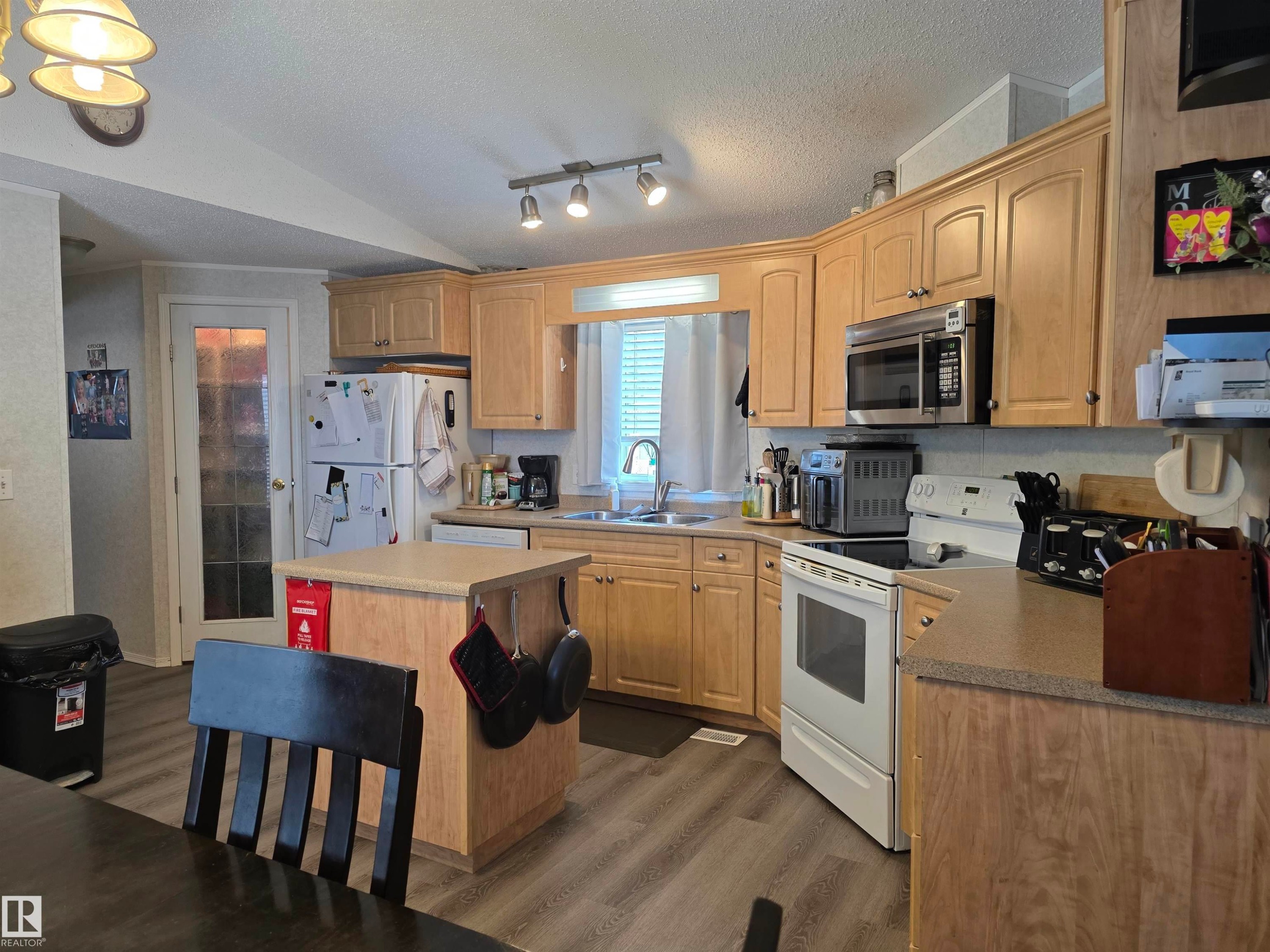 Kitchen featuring wood-finish cabinetry, track lighting, and a center island - 5012 53 Ave, Breton, AB