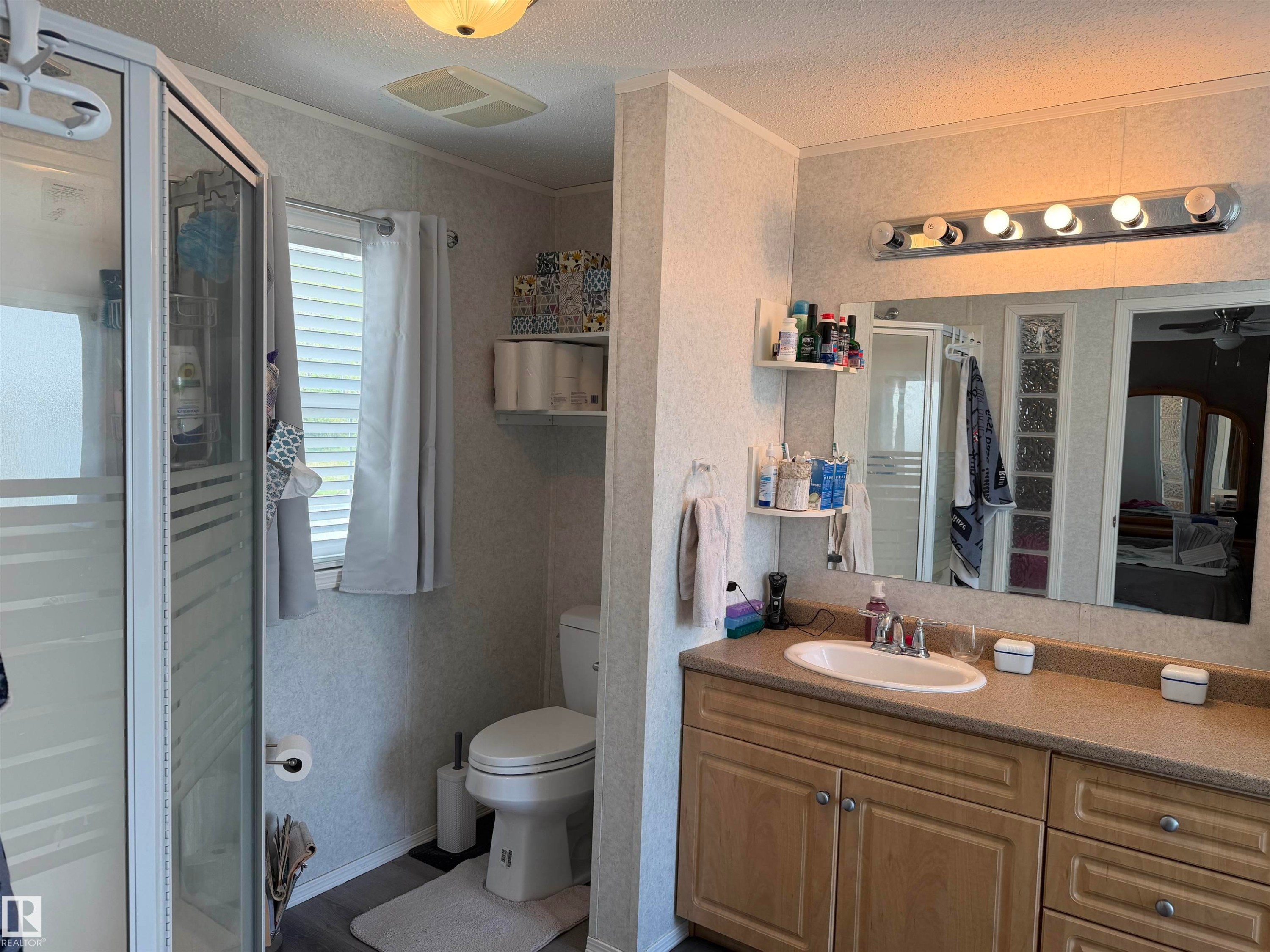Bathroom vanity featuring light wood-finish cabinetry, a single basin sink, and a light-toned countertop - 5012 53 Ave, Breton, AB