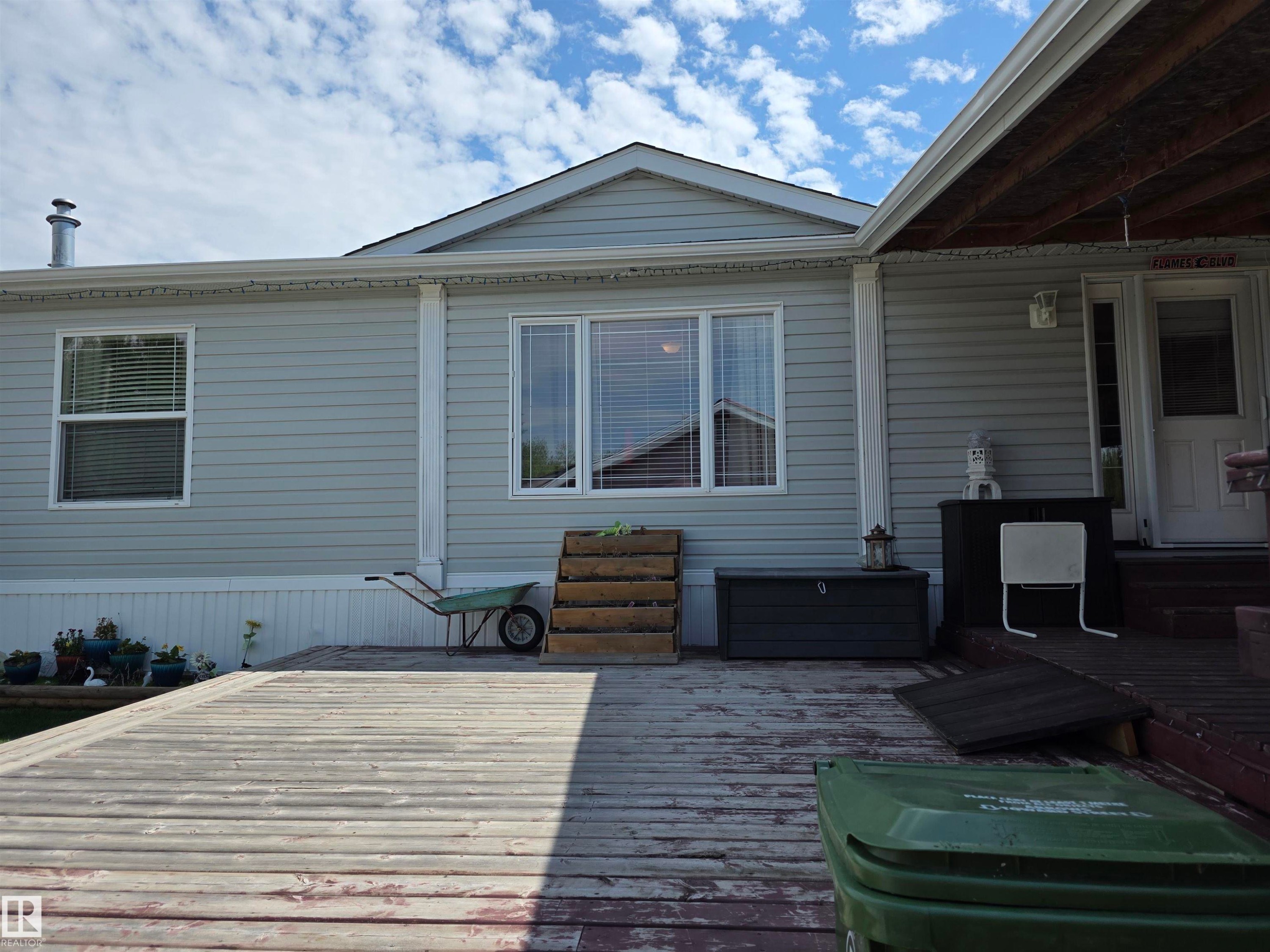 Expansive deck with visible wood grain and covered patio area - 5012 53 Ave, Breton, AB