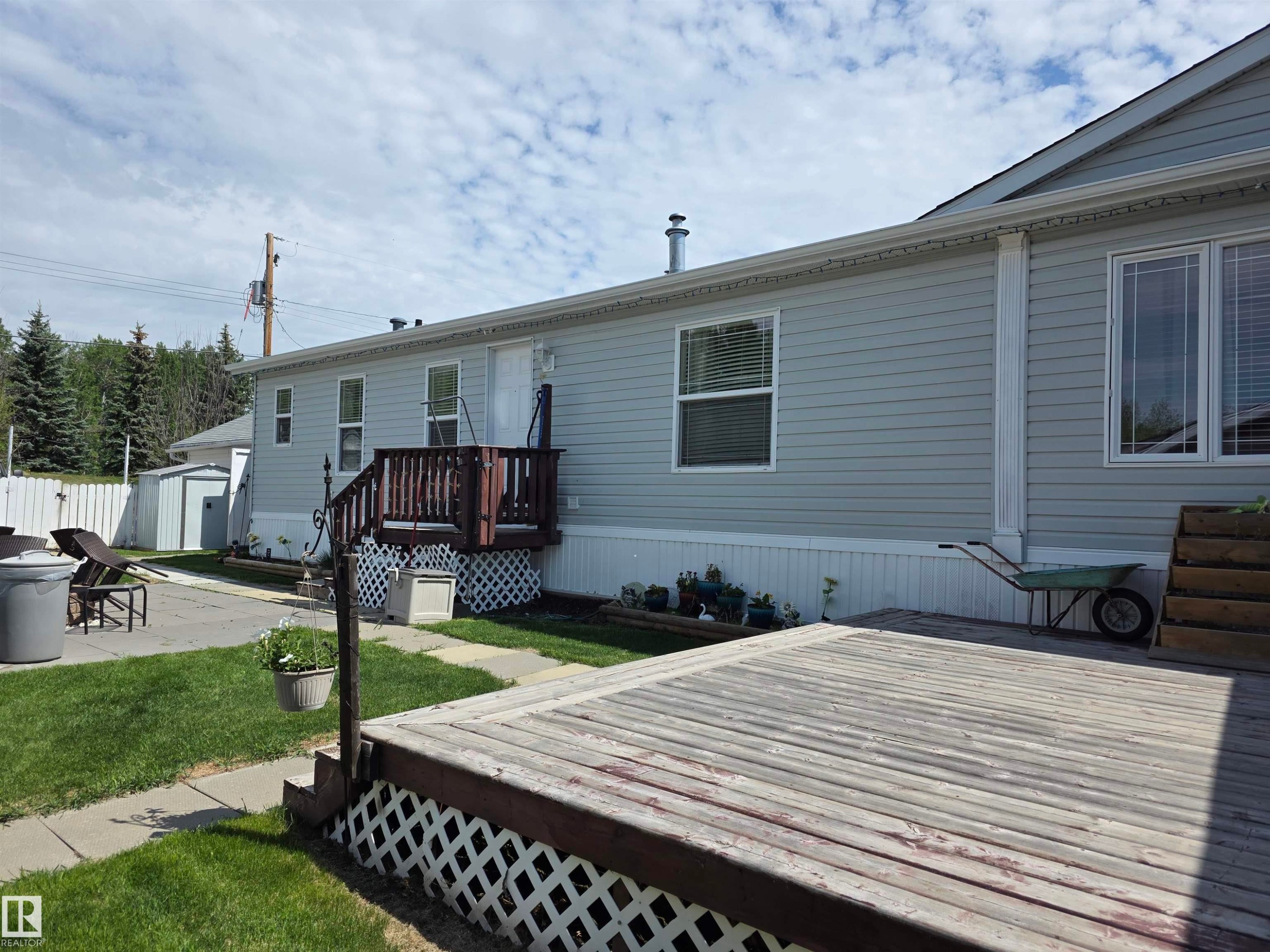 Rear exterior featuring light gray siding, white trim, and multiple windows - 5012 53 Ave, Breton, AB