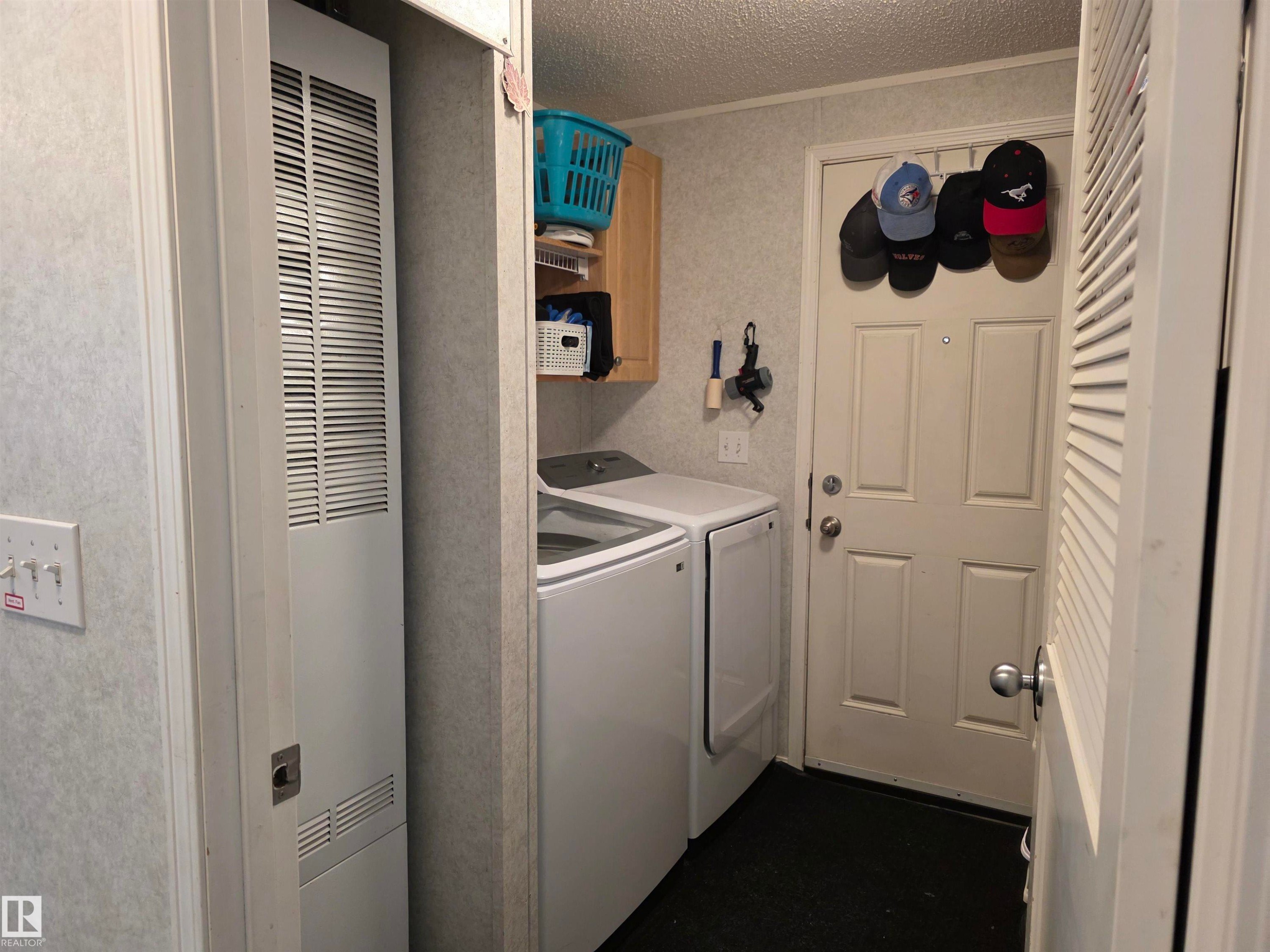laundry area featuring modern white appliances, a built-in cabinet, and wall-mounted shelving - 5012 53 Ave, Breton, AB