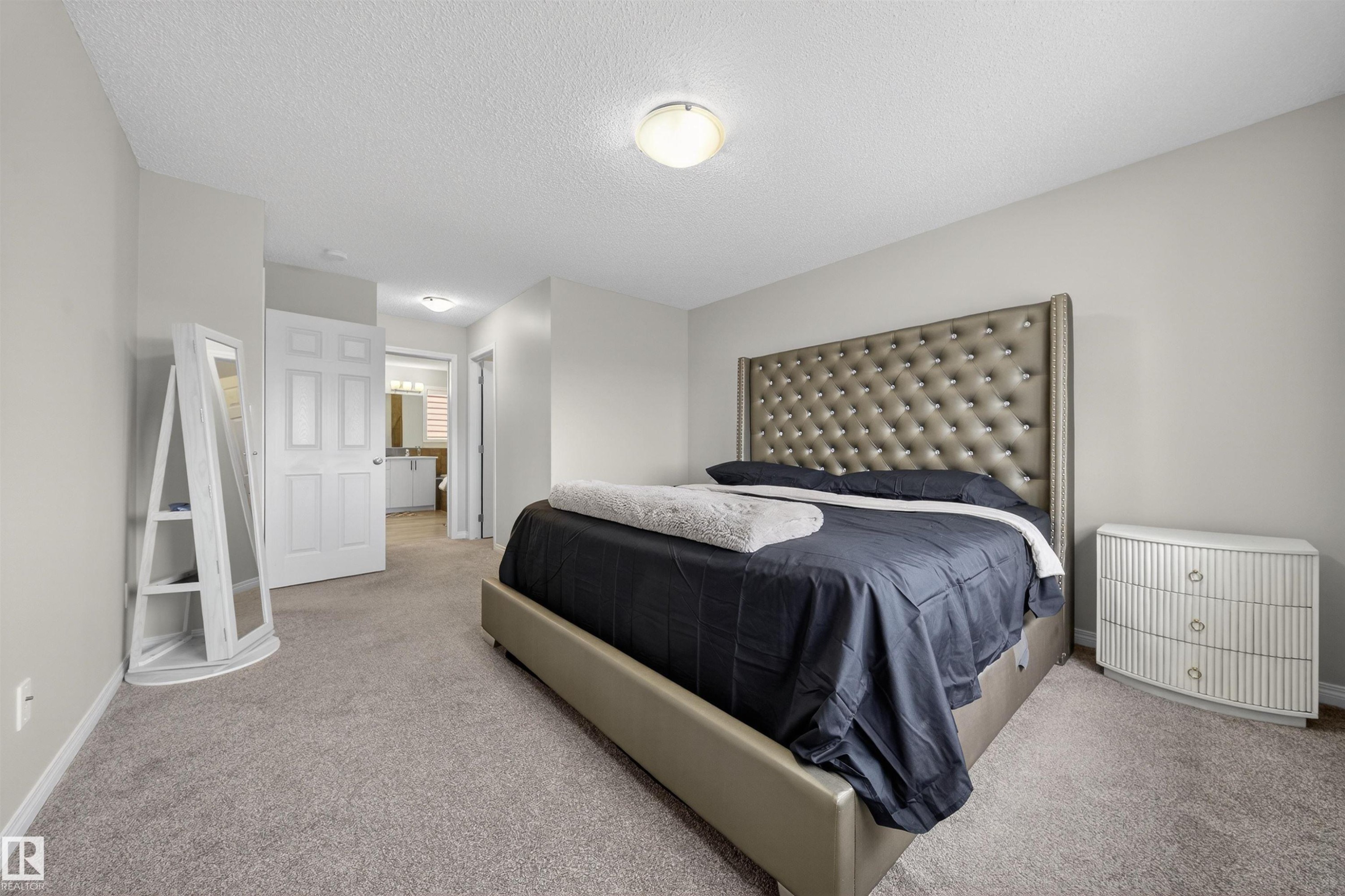Carpeted bedroom featuring a neutral color palette, recessed lighting, and a doorway opening to a bathroom with a vanity and mirror - 6085 King Landing, Edmonton, AB - Indoor Photo Showing Bedroom