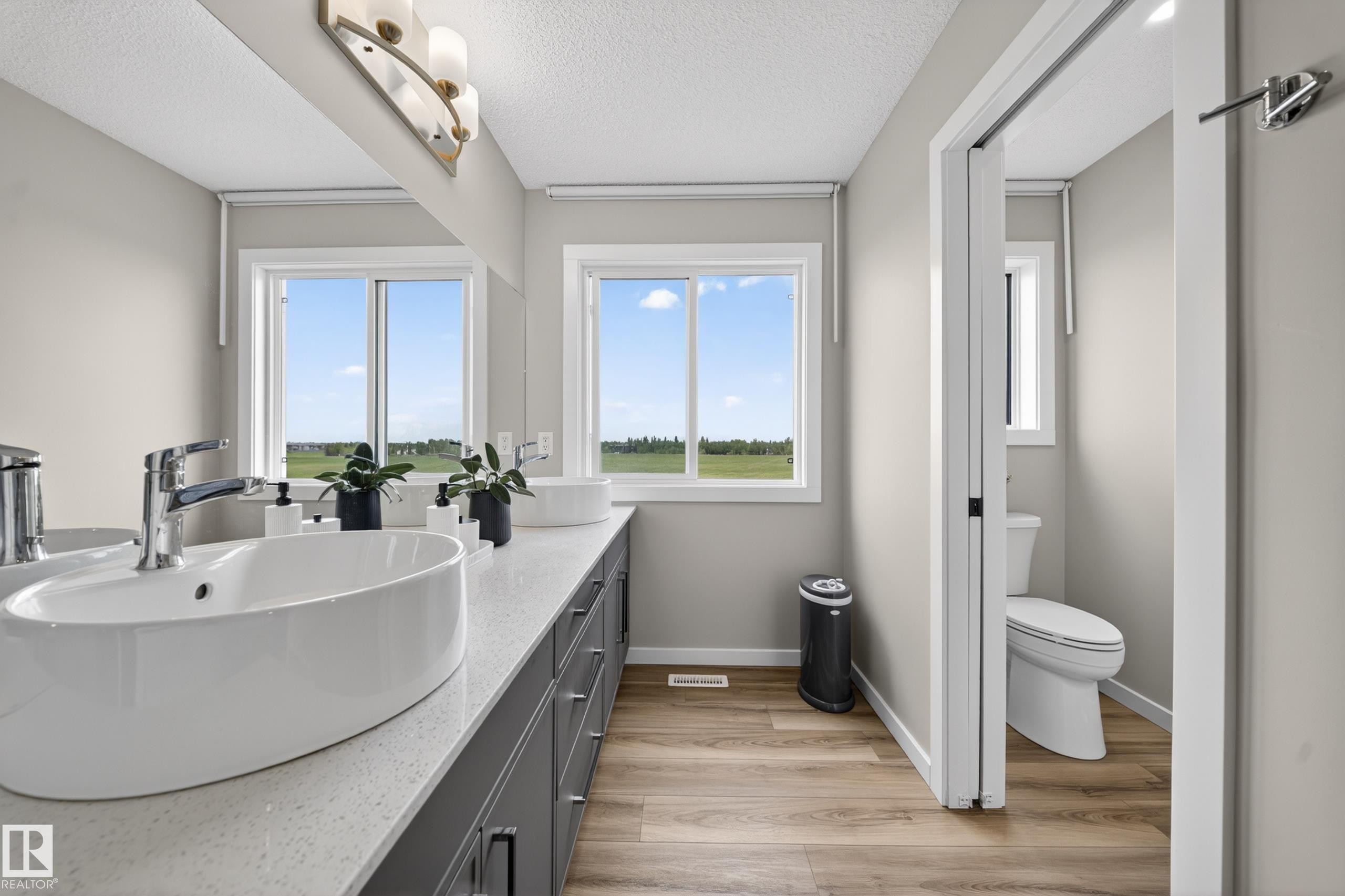 Dual vessel sinks set on an extended vanity with a light-colored countertop - 3337 Kulay Way, Edmonton, AB - Indoor Photo Showing Bathroom