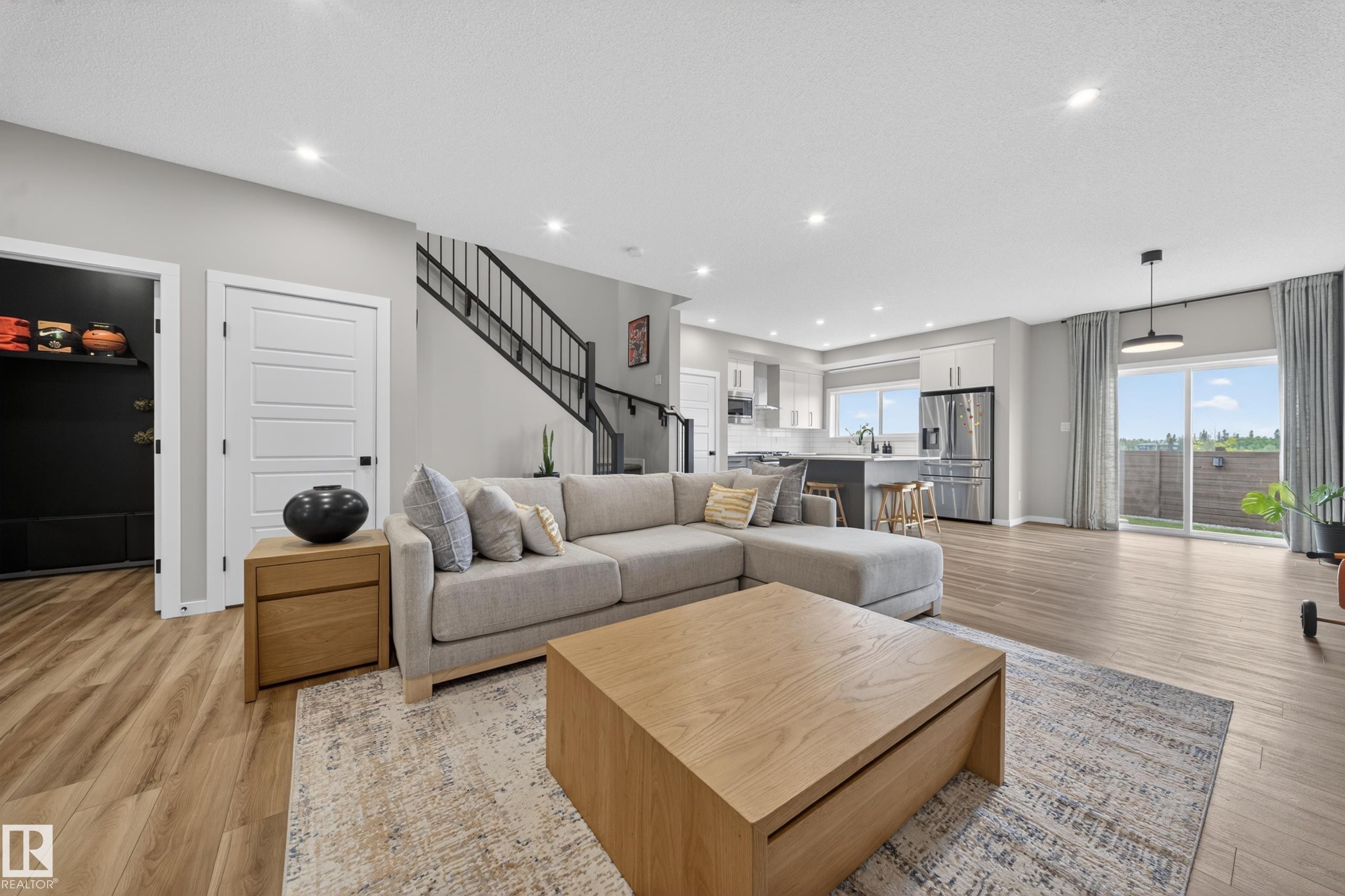 Open concept living area featuring wood-finish flooring, recessed lighting, and a sliding glass door to the exterior - 3337 Kulay Way, Edmonton, AB - Indoor Photo Showing Living Room