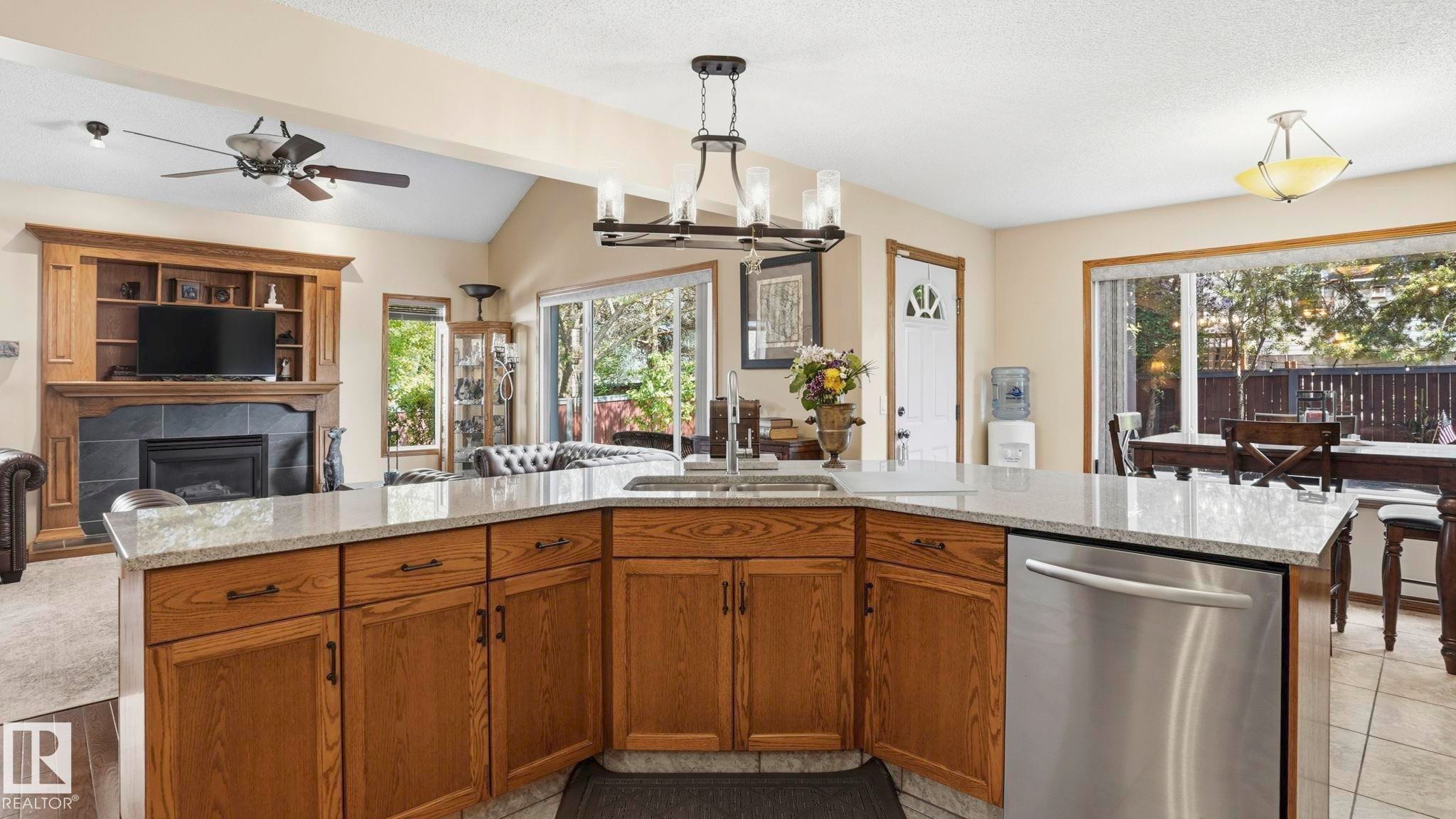 Kitchen island featuring granite-style countertops, integrated sink, and stainless steel dishwasher - 4309 37A Avenue, Edmonton, AB - Indoor Photo Showing Kitchen With Double Sink