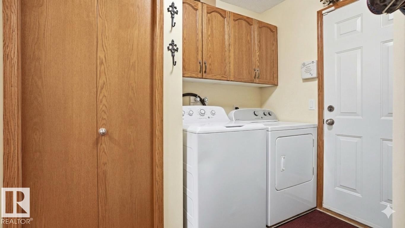 Laundry area featuring upper wood cabinetry, white appliances, and a solid wood bifold door - 4309 37A Avenue, Edmonton, AB - Indoor Photo Showing Laundry Room