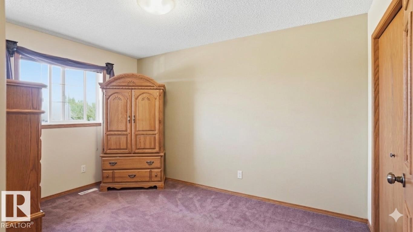 Bright interior room featuring a large window with white trim, neutral wall paint, and purple carpeting - 4309 37A Avenue, Edmonton, AB - Indoor