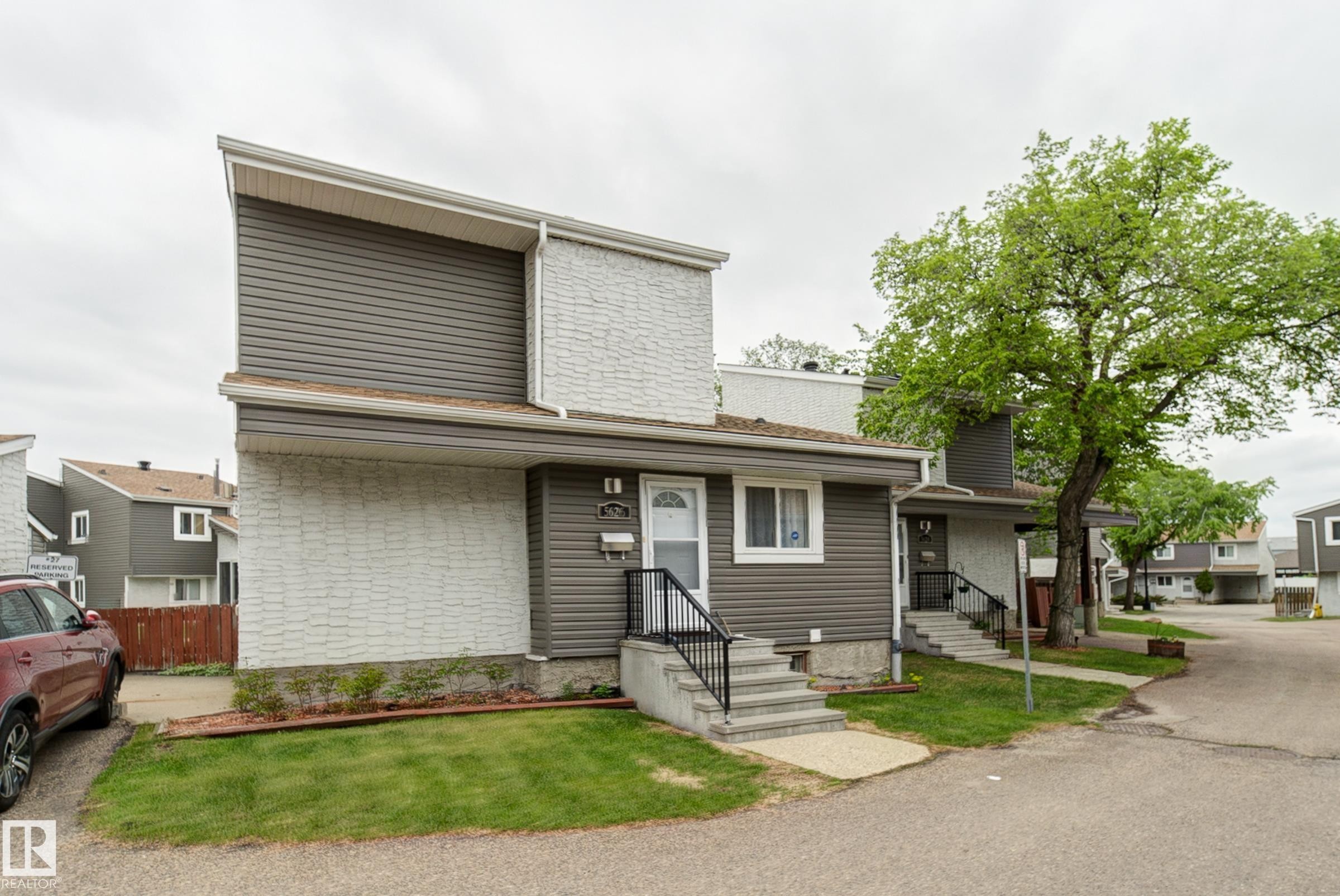 Two-story townhouse exterior with horizontal siding and textured paneling - 5626 19A Avenue, Edmonton, AB