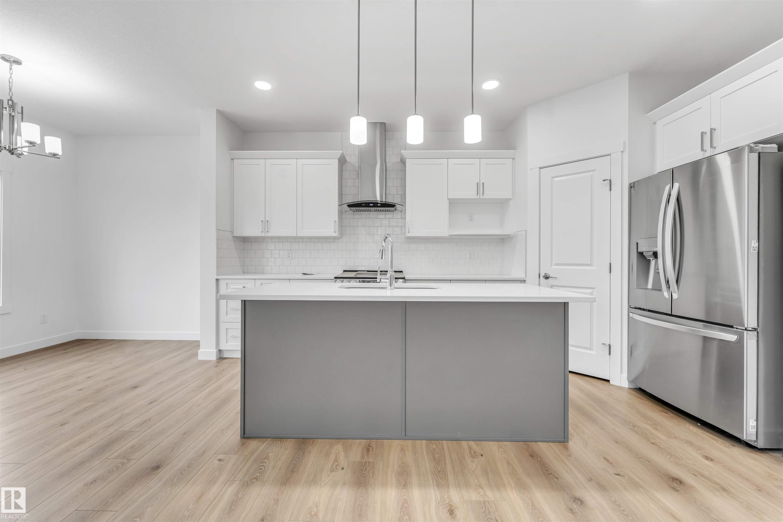 Modern kitchen featuring a gray island, white cabinetry, stainless steel appliances, and wood-finish flooring - 1972 210 Street, Edmonton, AB - Indoor Photo Showing Kitchen With Double Sink