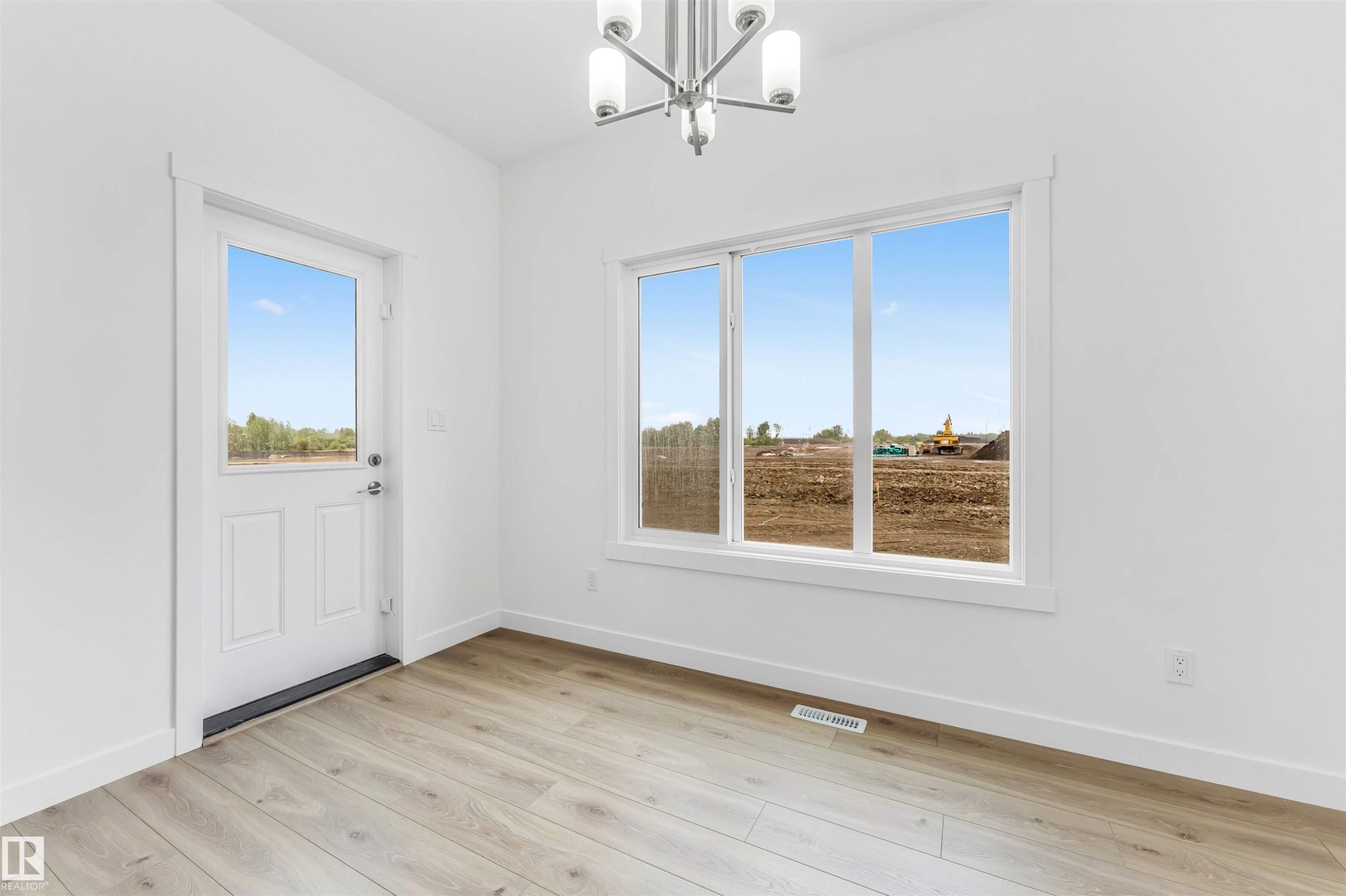 Room featuring wood-finish flooring, a contemporary chandelier, a multi-pane window, a paneled door with glass insert, and white baseboards - 1972 210 Street, Edmonton, AB - Indoor Photo Showing Other Room