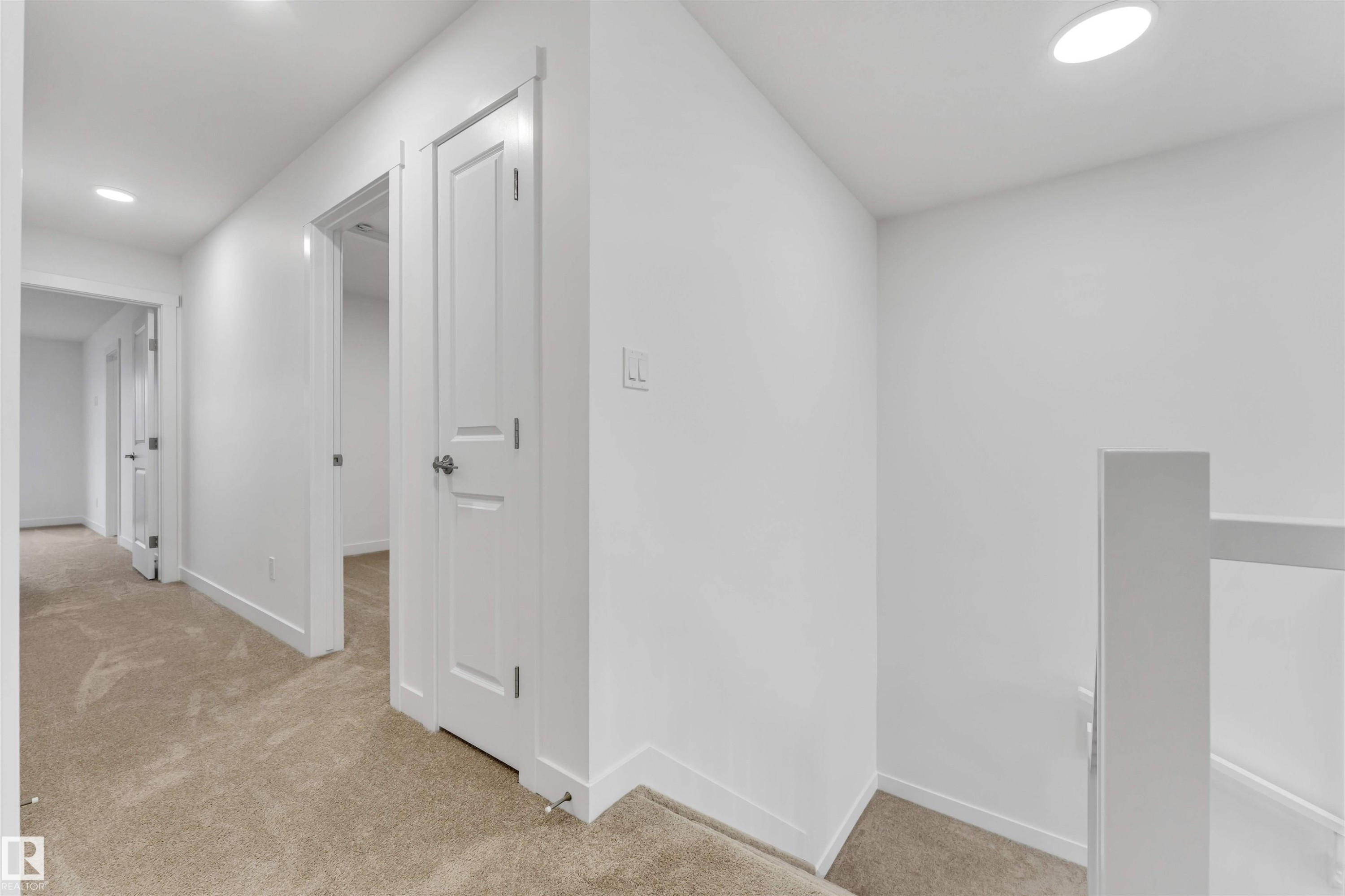 Hallway with neutral carpeting, white walls, recessed ceiling lighting, and panel doors with modern hardware - 1972 210 Street, Edmonton, AB - Indoor Photo Showing Other Room