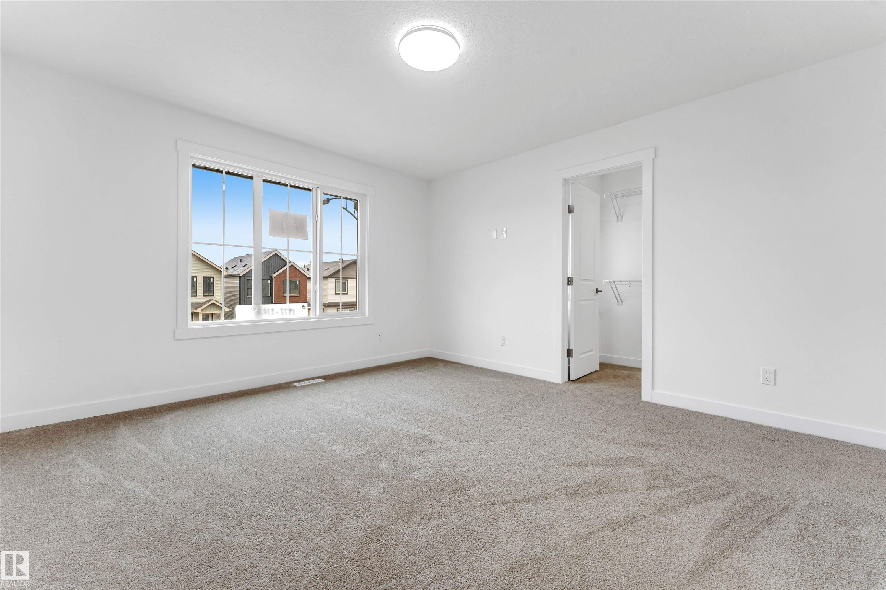 Expansive room featuring plush grey carpeting, a large multipane window, and a bright overhead ceiling light - 1972 210 Street, Edmonton, AB - Indoor Photo Showing Other Room