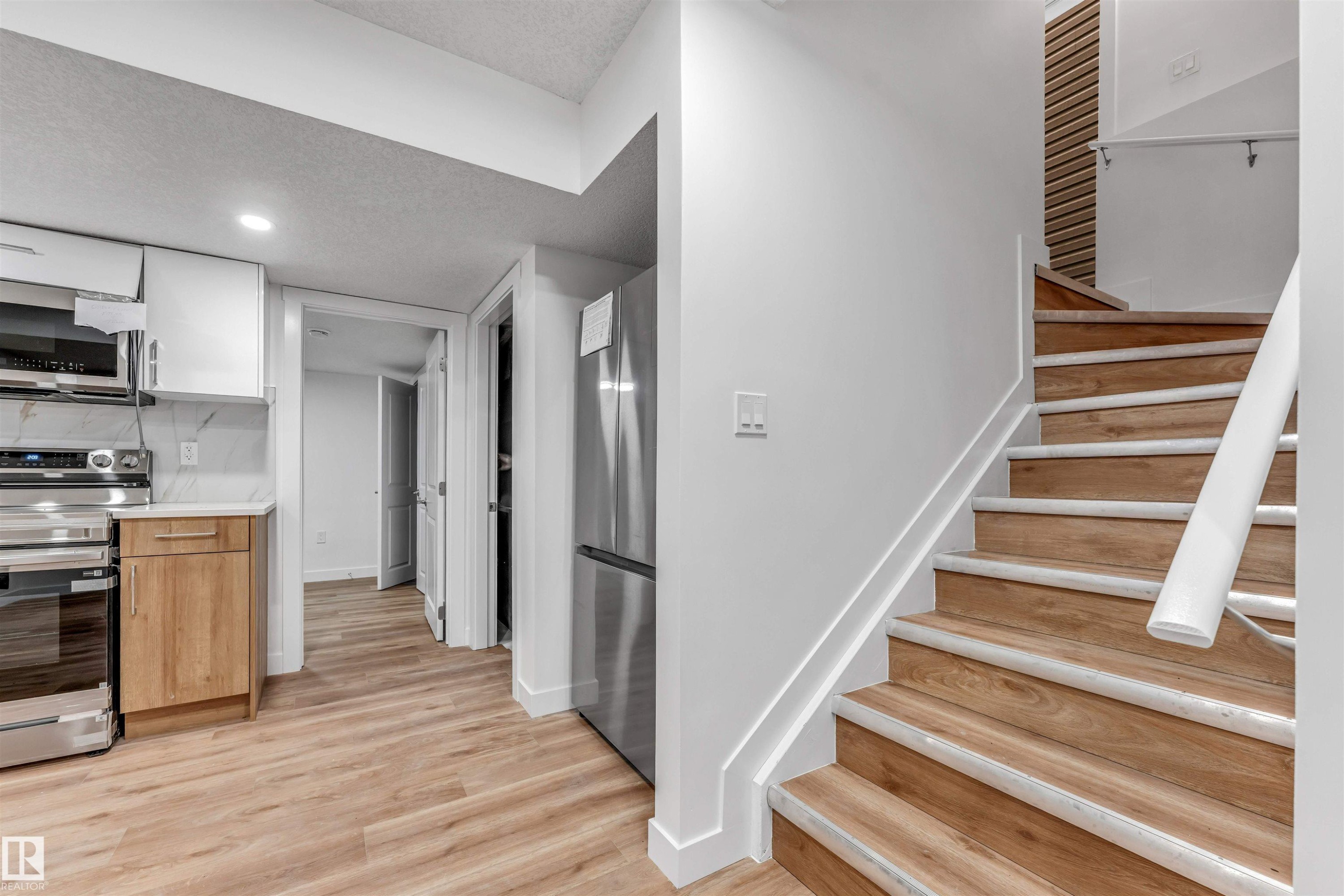 Modern staircase featuring wood-finish treads and a white handrail - 1972 210 Street, Edmonton, AB - Indoor