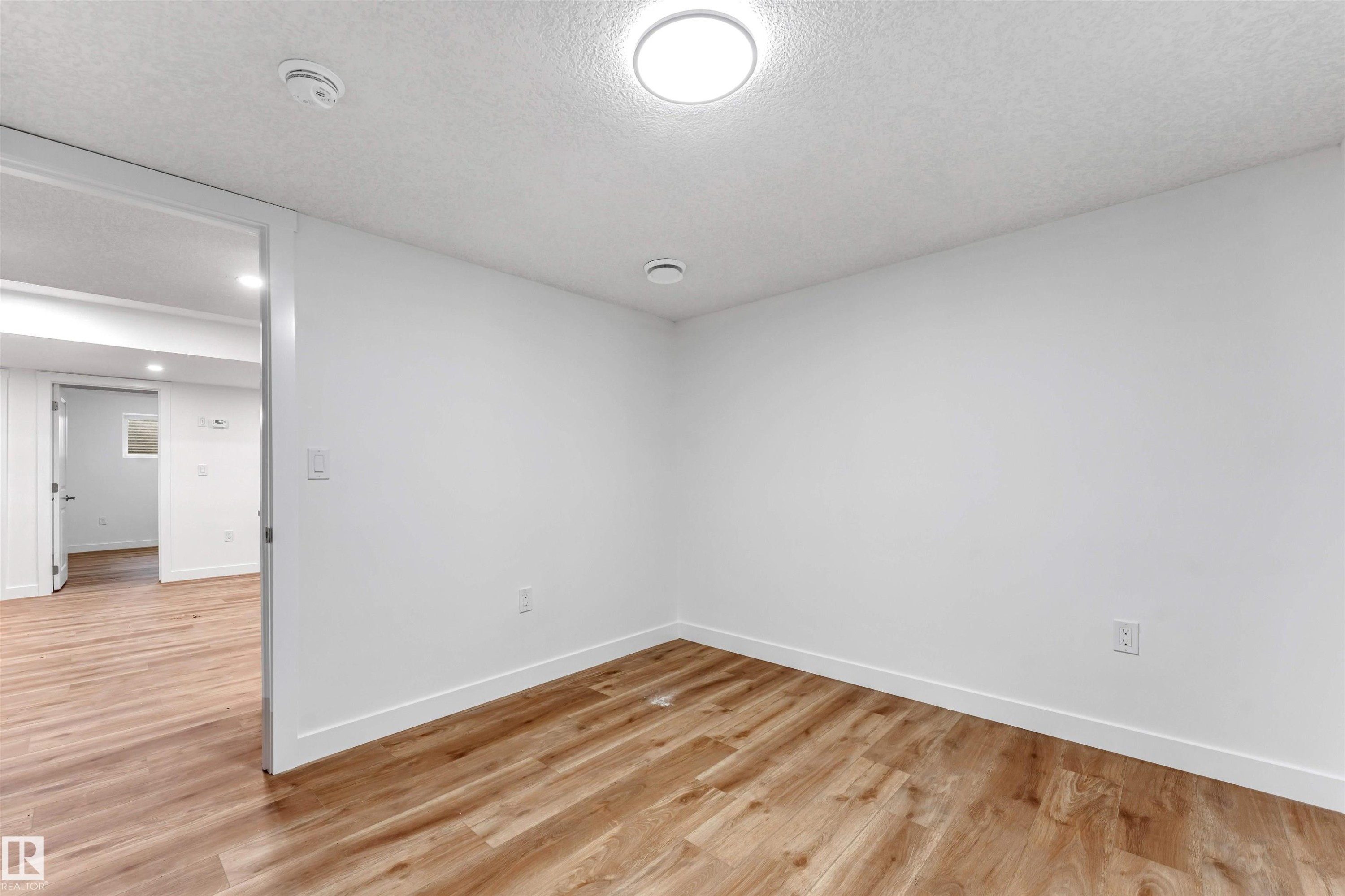 Spacious room featuring wood-finish flooring, crisp white walls, and recessed lighting - 1972 210 Street, Edmonton, AB - Indoor Photo Showing Other Room