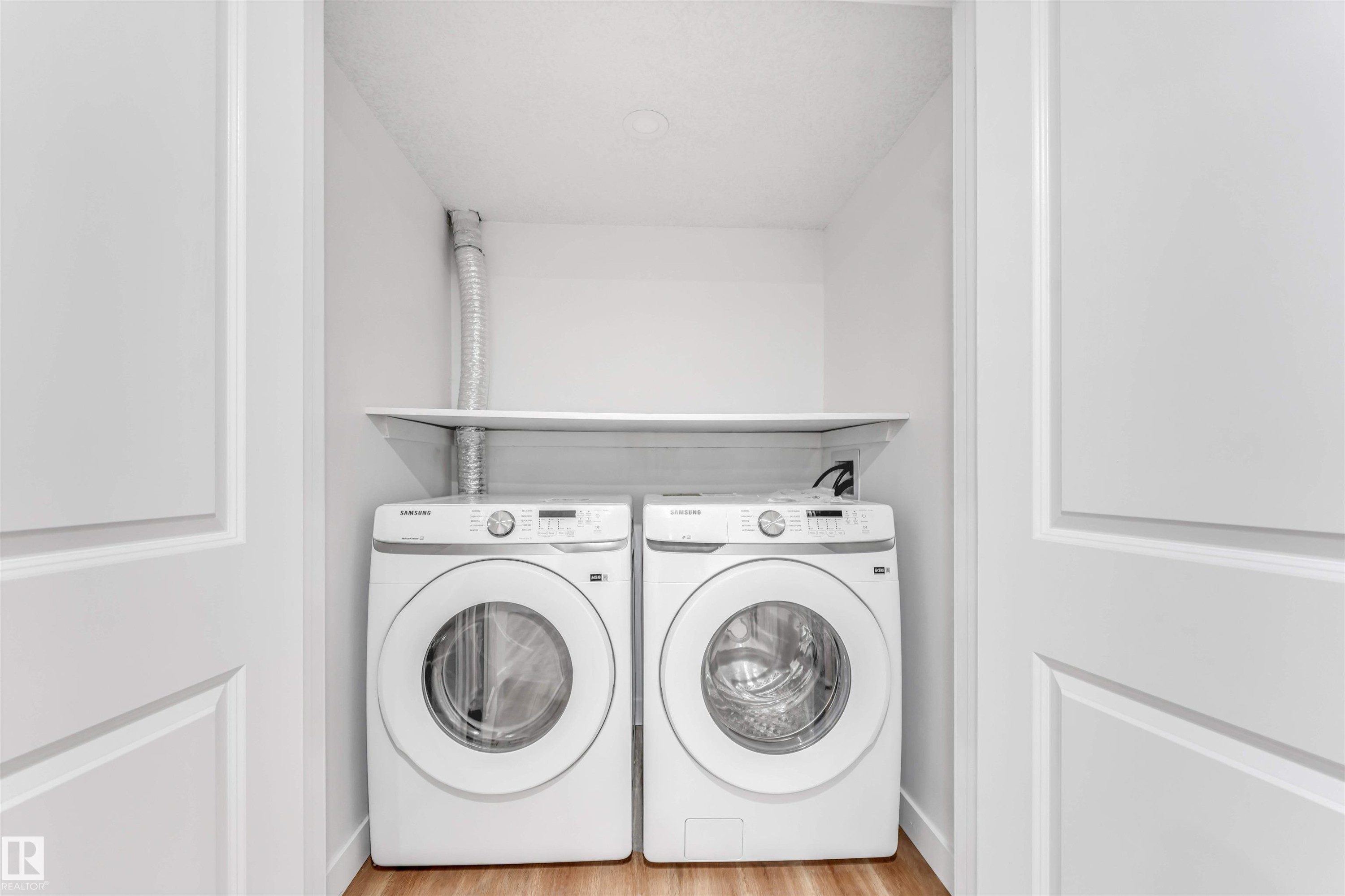 Dedicated laundry closet featuring a built-in shelf and wood-finish flooring - 1972 210 Street, Edmonton, AB - Indoor Photo Showing Laundry Room