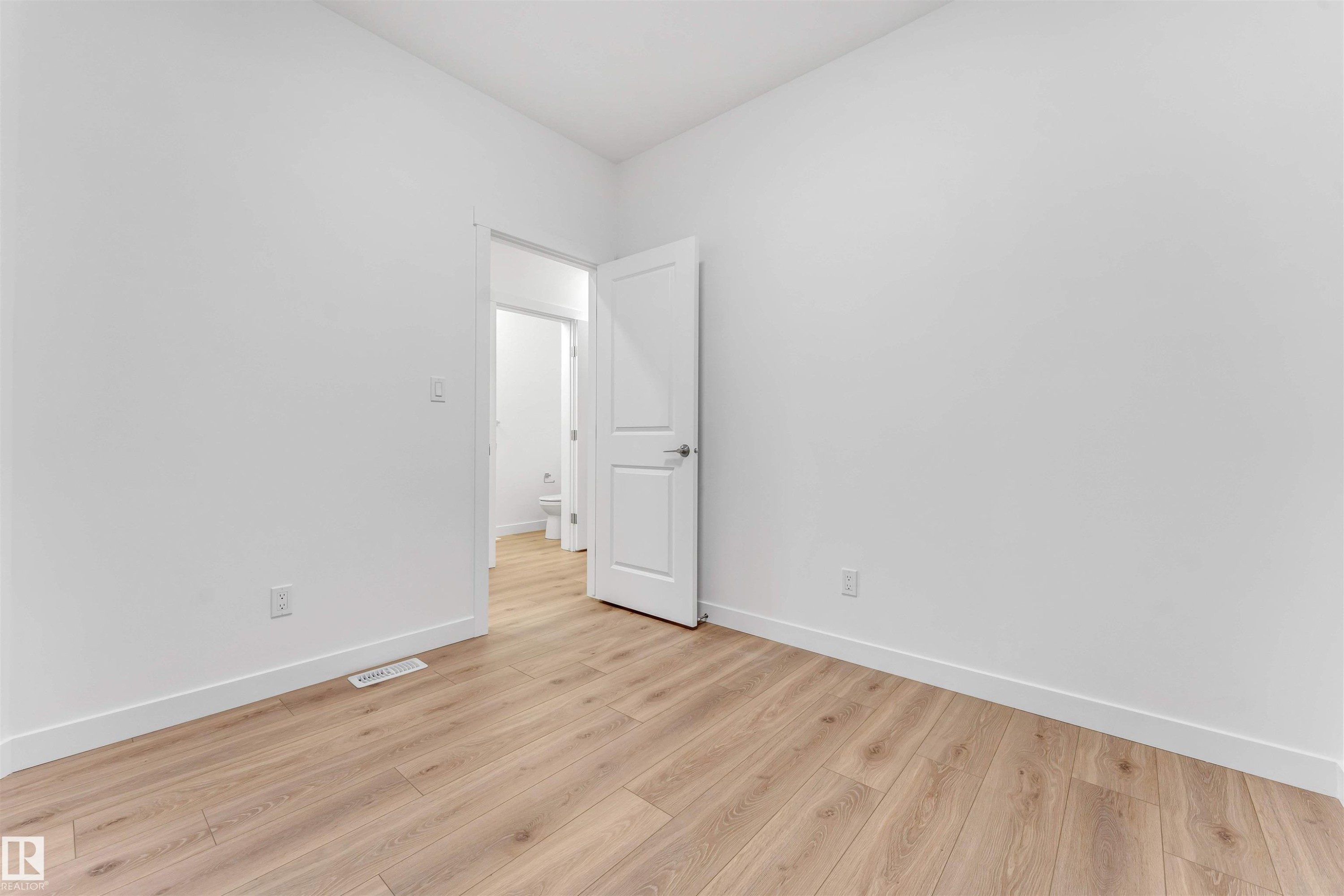 Spacious room featuring light wood-finish flooring, white walls, and a contemporary white interior door - 1972 210 Street, Edmonton, AB - Indoor Photo Showing Other Room