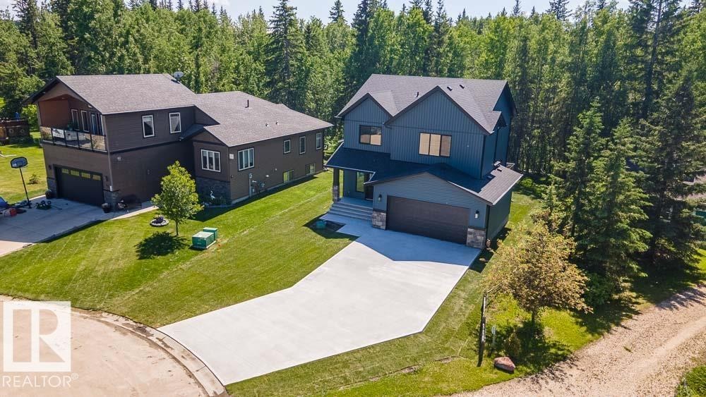 Contemporary two-story residence featuring dark blue vertical siding, a stone accent facade, and a dark asphalt shingle roof - 132 Heron Point Close, Rural Wetaskiwin County, AB