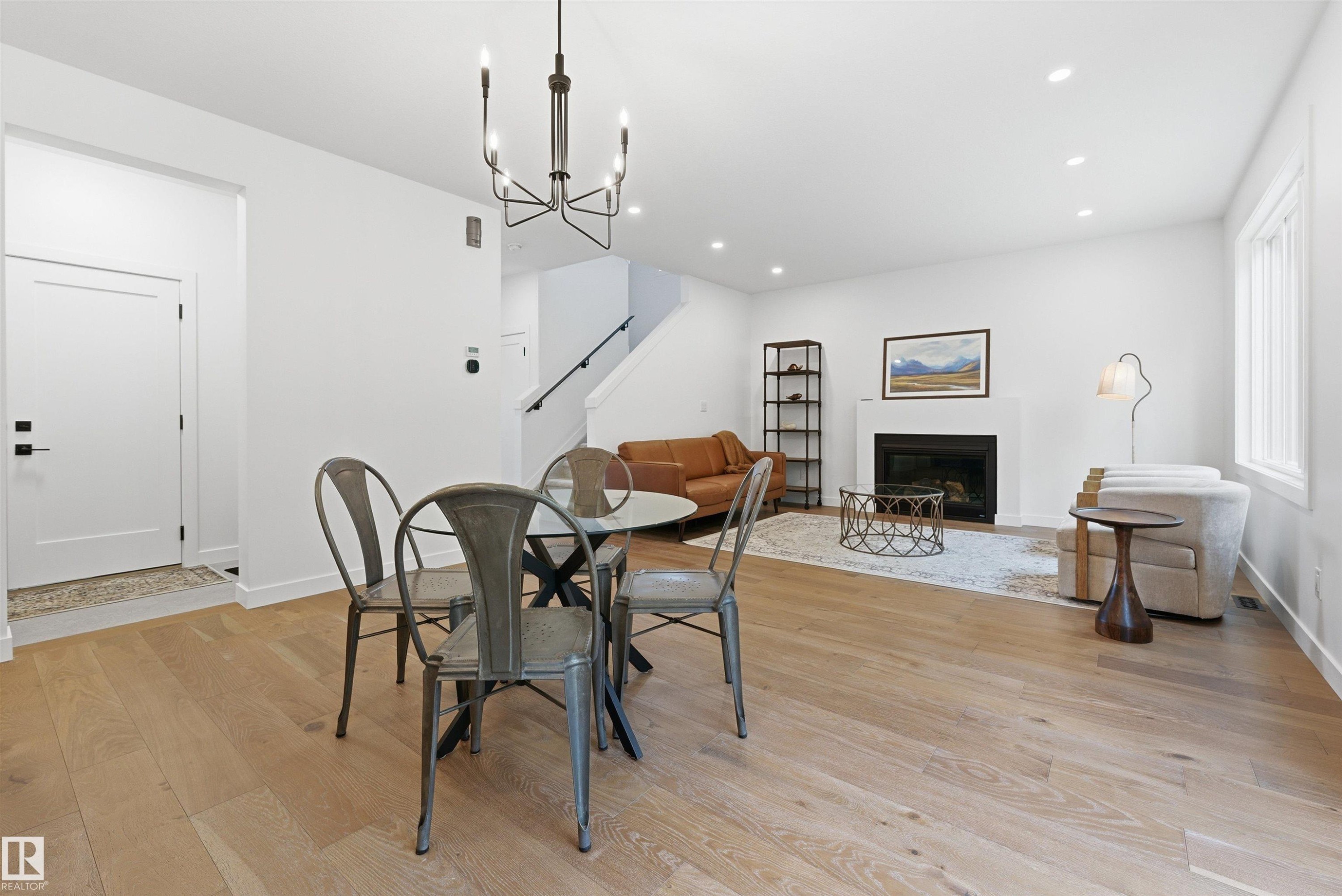 Open-concept living space featuring wood-finish flooring, a contemporary chandelier, recessed lighting, a built-in fireplace, and a large window - 132 Heron Point Close, Rural Wetaskiwin County, AB