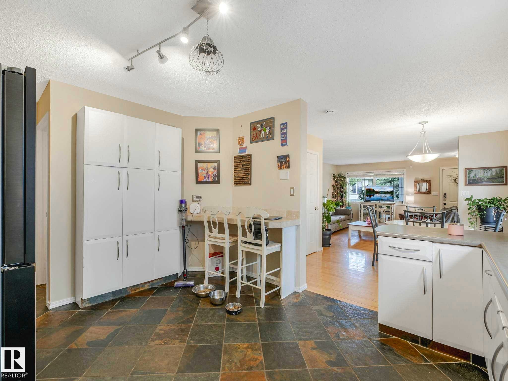 Kitchen featuring slate tile flooring, extensive white cabinetry, a built-in breakfast bar, and recessed lighting - 4031 38 Street, Edmonton, AB