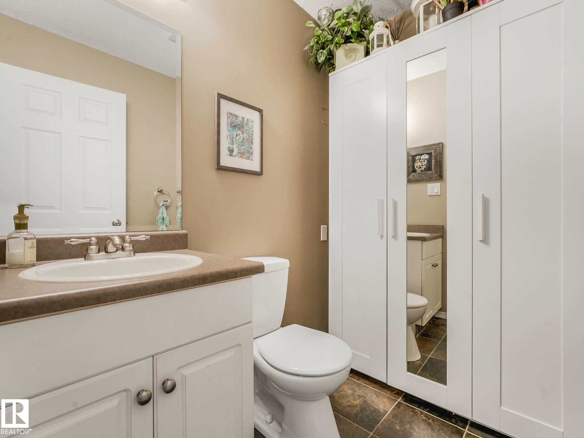 Bathroom featuring a white vanity with an undermount sink, a countertop with a subtle pattern, and a coordinating toilet - 4031 38 Street, Edmonton, AB