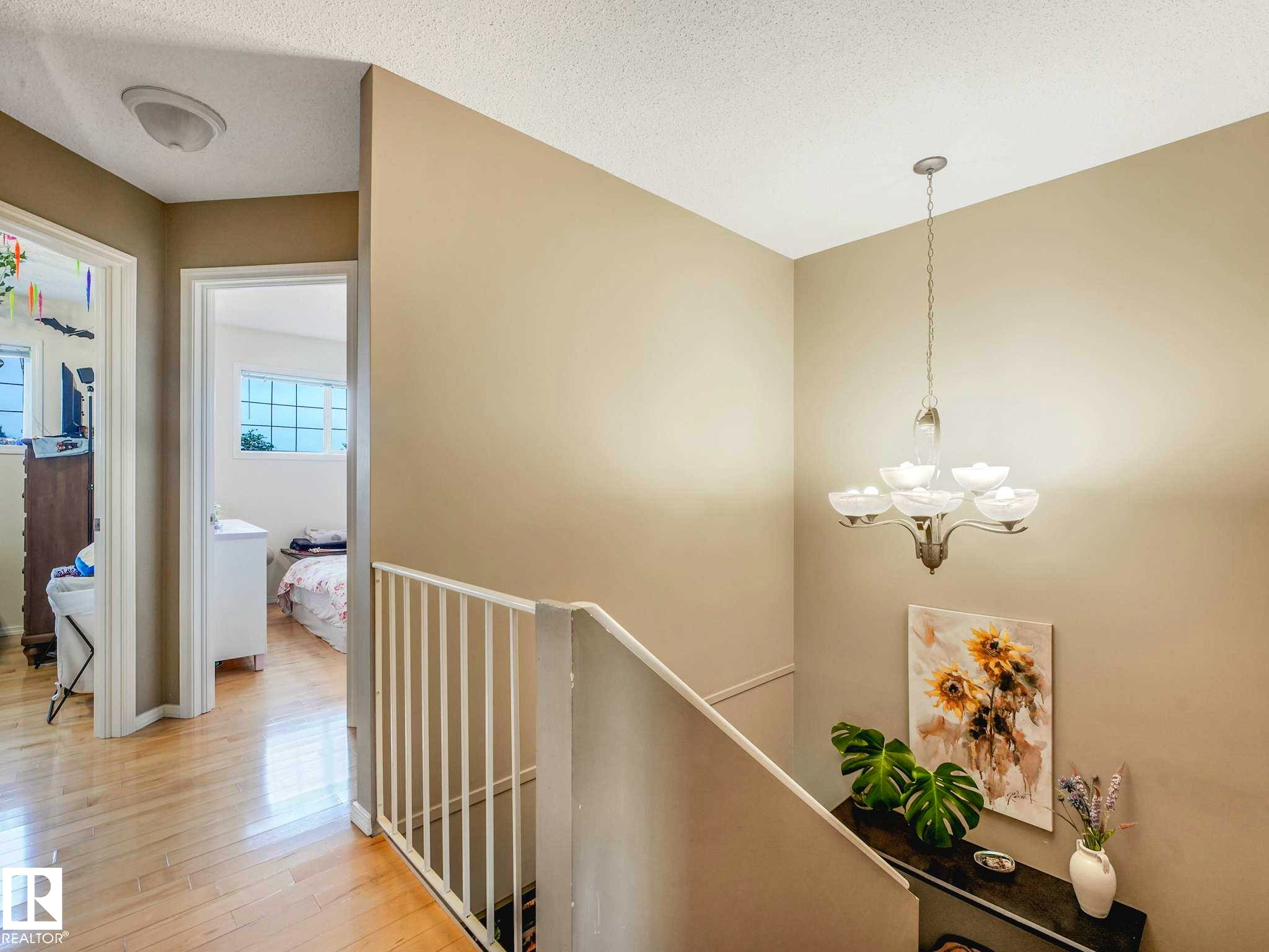 Upper landing featuring hardwood flooring, a contemporary ceiling light fixture, and a white baluster railing - 4031 38 Street, Edmonton, AB