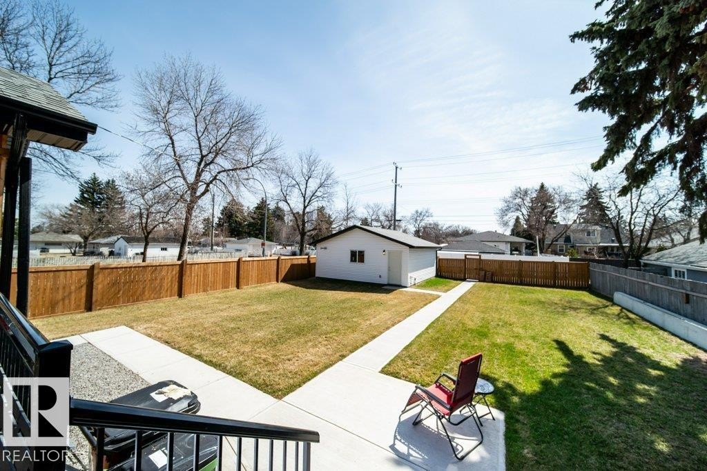 Expansive backyard featuring a manicured lawn, a detached white auxiliary building, and a privacy fence - 11303 111 Avenue, Edmonton, AB - Outdoor With Backyard