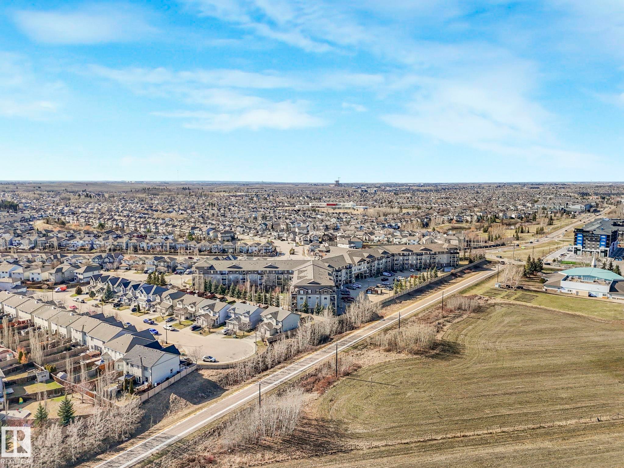 Expansive aerial showing a residential area with varied housing types, including multi-story townhomes and apartment buildings - 322 1520 Hammond Gate Nw, Edmonton, AB - Outdoor With View
