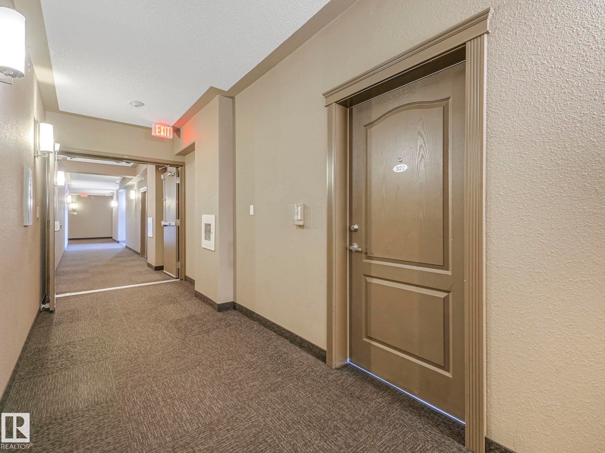 Contemporary hallway featuring textured neutral-toned walls, recessed lighting, and sconce fixtures - 322 1520 Hammond Gate Nw, Edmonton, AB - Indoor Photo Showing Other Room