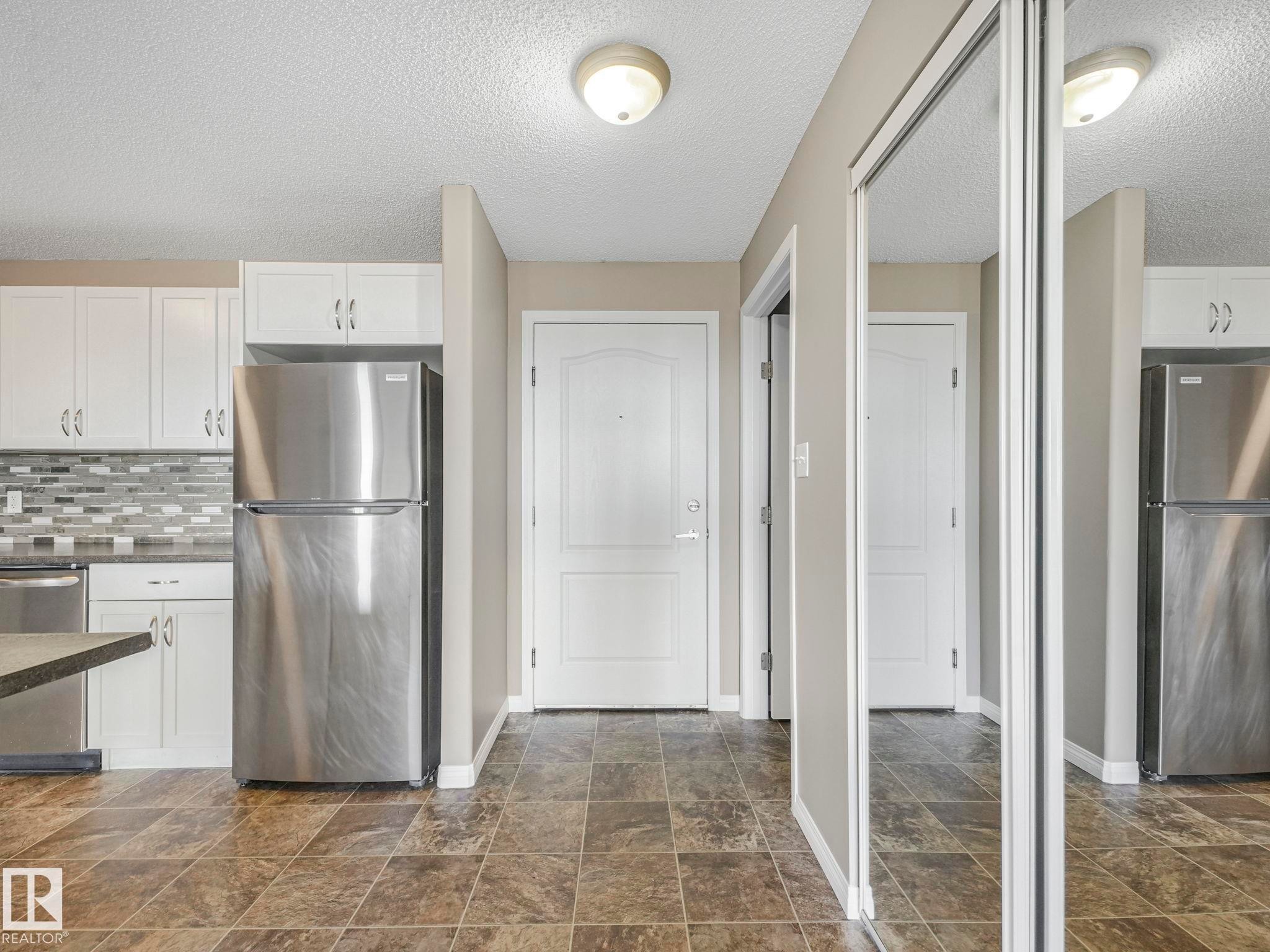 Kitchen with white cabinetry, stainless steel appliances, and a mosaic tile backsplash - 322 1520 Hammond Gate Nw, Edmonton, AB - Indoor Photo Showing Kitchen With Double Sink