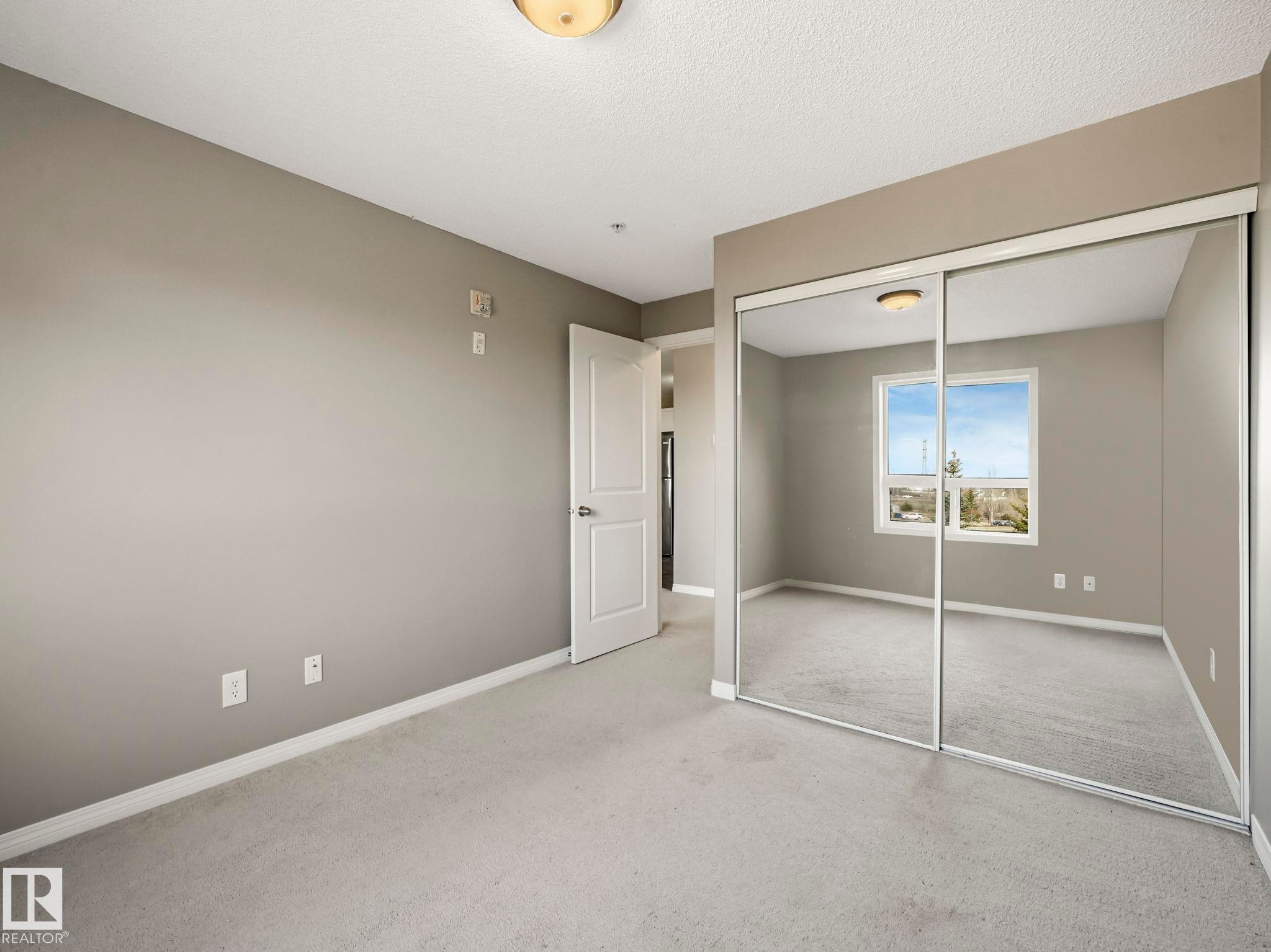 Bedroom featuring neutral wall paint, light-colored carpeting, white baseboards, and a white two-panel interior door - 322 1520 Hammond Gate Nw, Edmonton, AB - Indoor Photo Showing Other Room