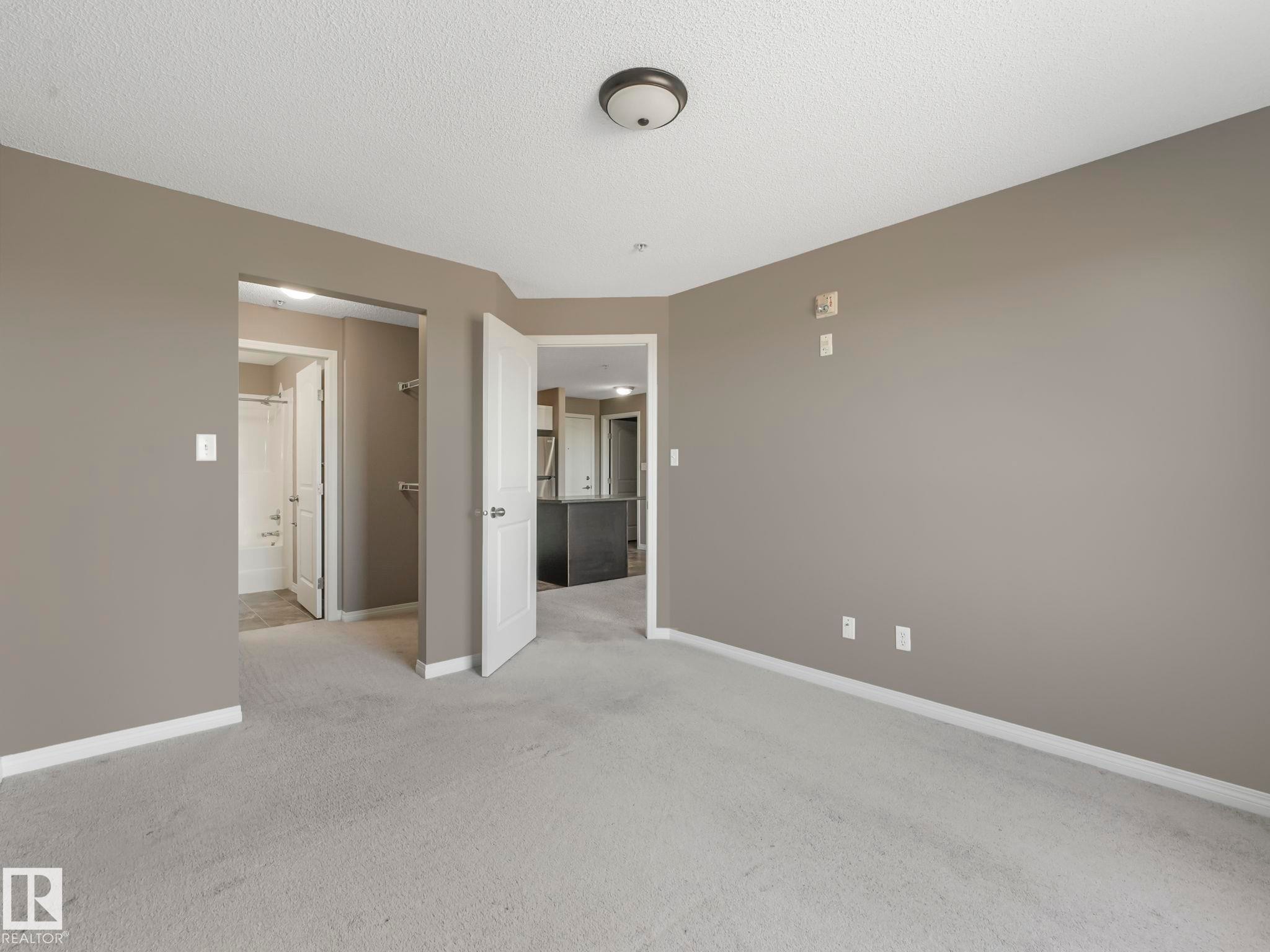Carpeted room with neutral wall paint and white trim - 322 1520 Hammond Gate Nw, Edmonton, AB - Indoor Photo Showing Other Room