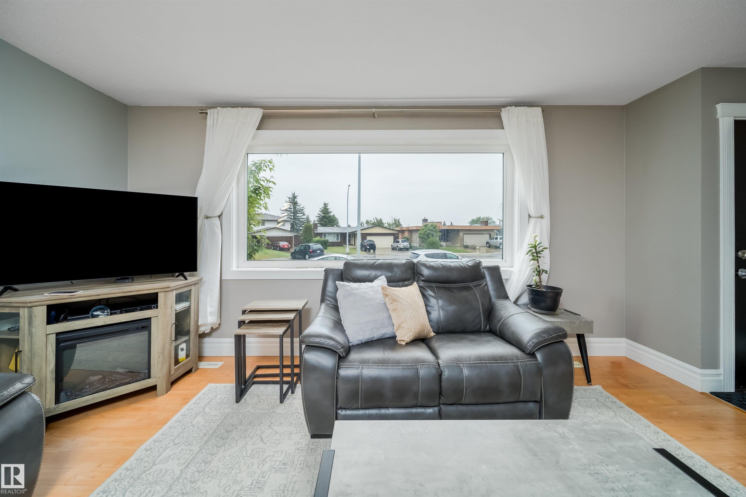 Bright living area featuring wood-finish flooring and a large picture window - 8512 142A Avenue, Edmonton, AB