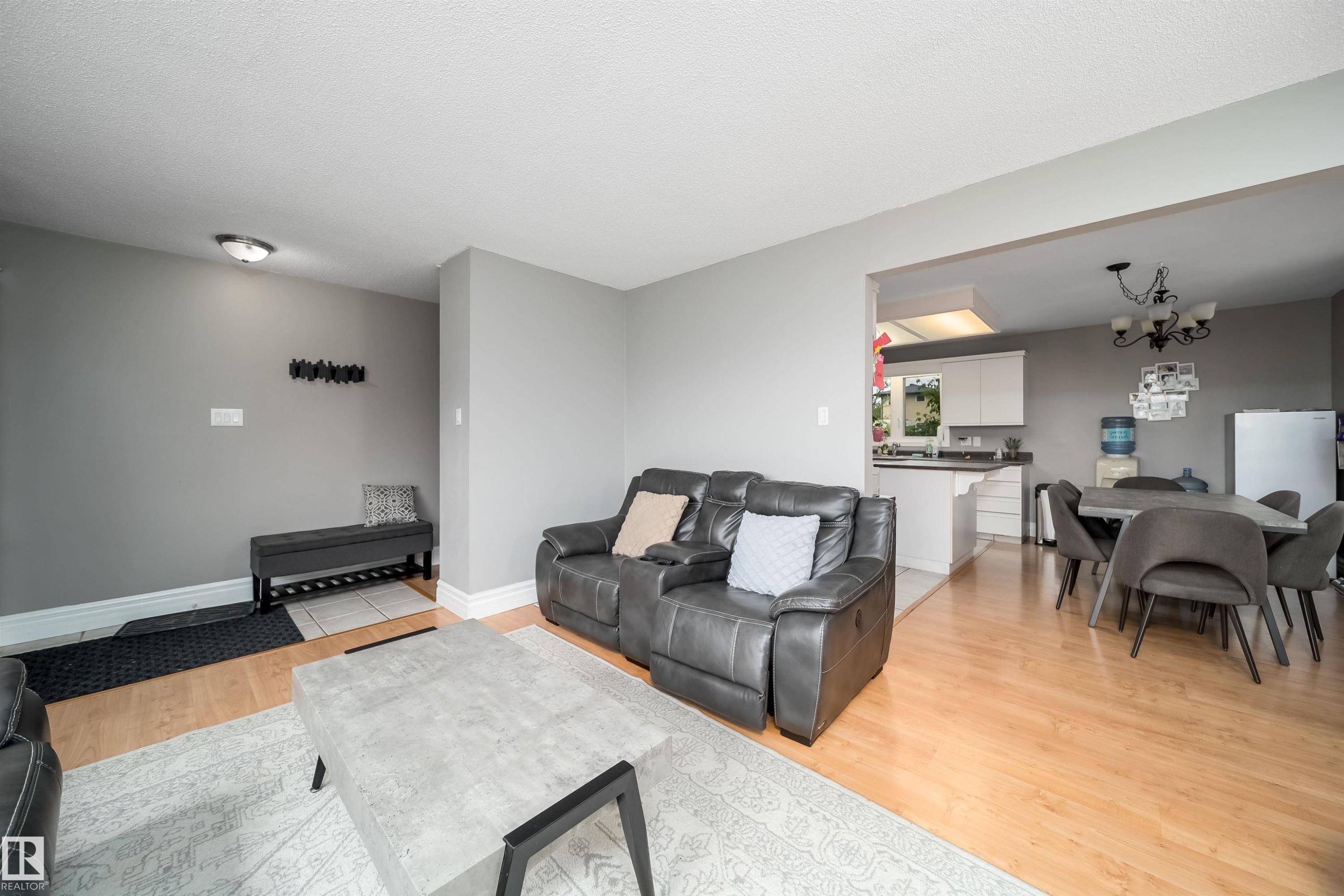 Living room featuring wood-finish flooring, light gray walls, and recessed lighting - 8512 142A Avenue, Edmonton, AB