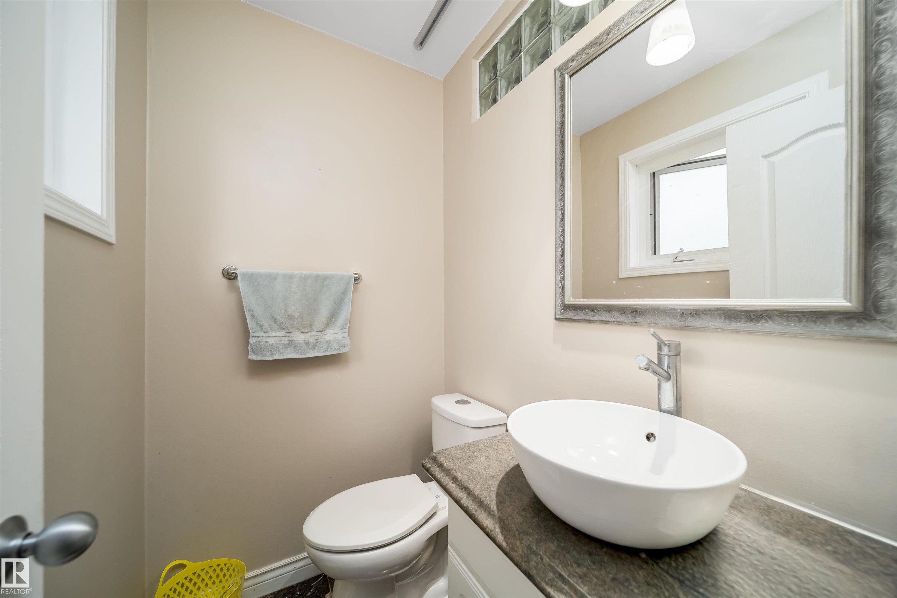 Bathroom featuring a contemporary vessel sink, dark wood-finish countertop, and decorative framed mirror - 8512 142A Avenue, Edmonton, AB